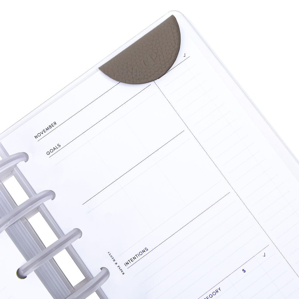 Contoured leather clip in use inside a discbound planner notebook.