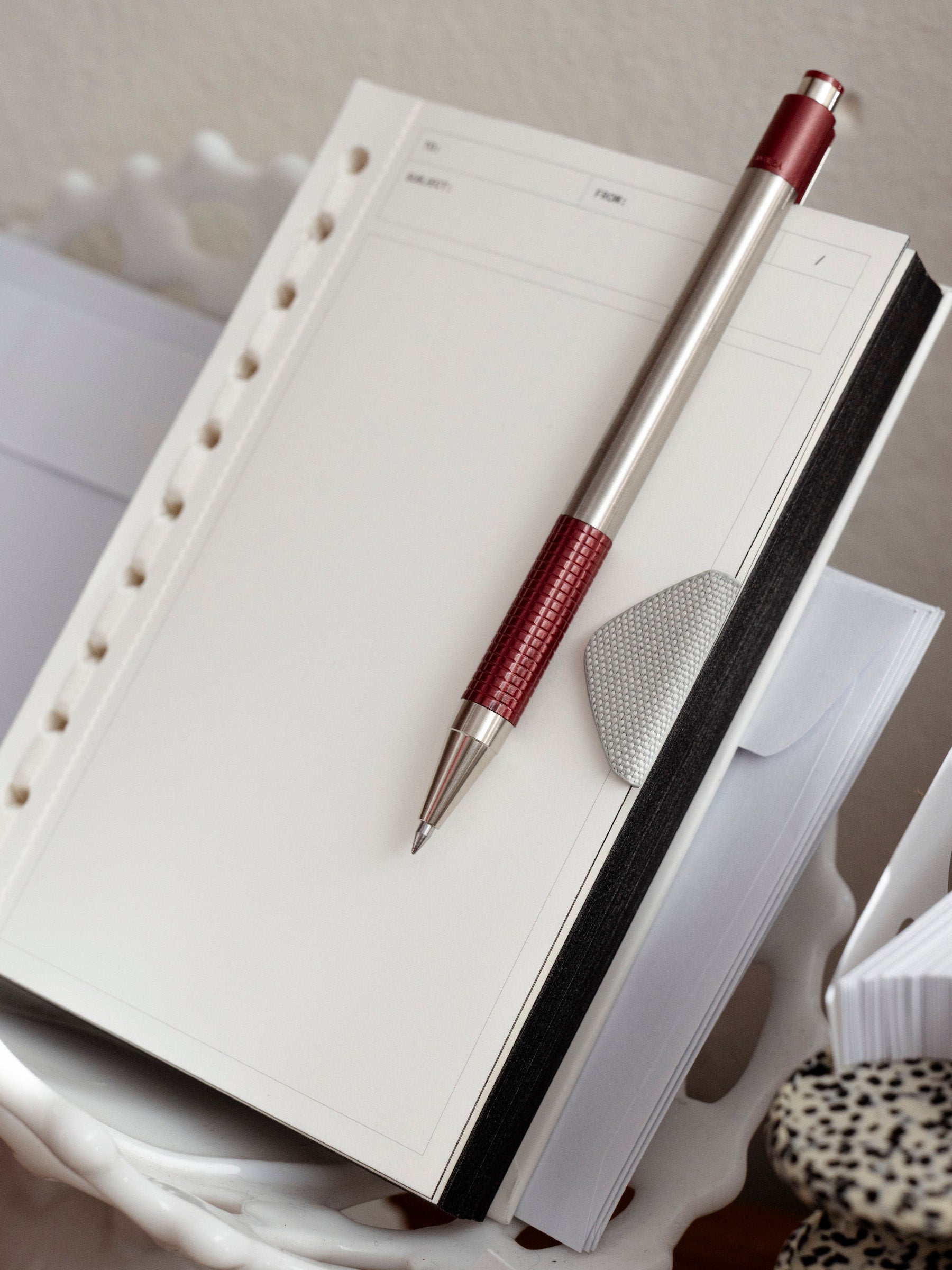 A high-angle, close-up shot of a cream-colored Message Pad from March Intention Box, resting in a white, scalloped-edge decorative tray.