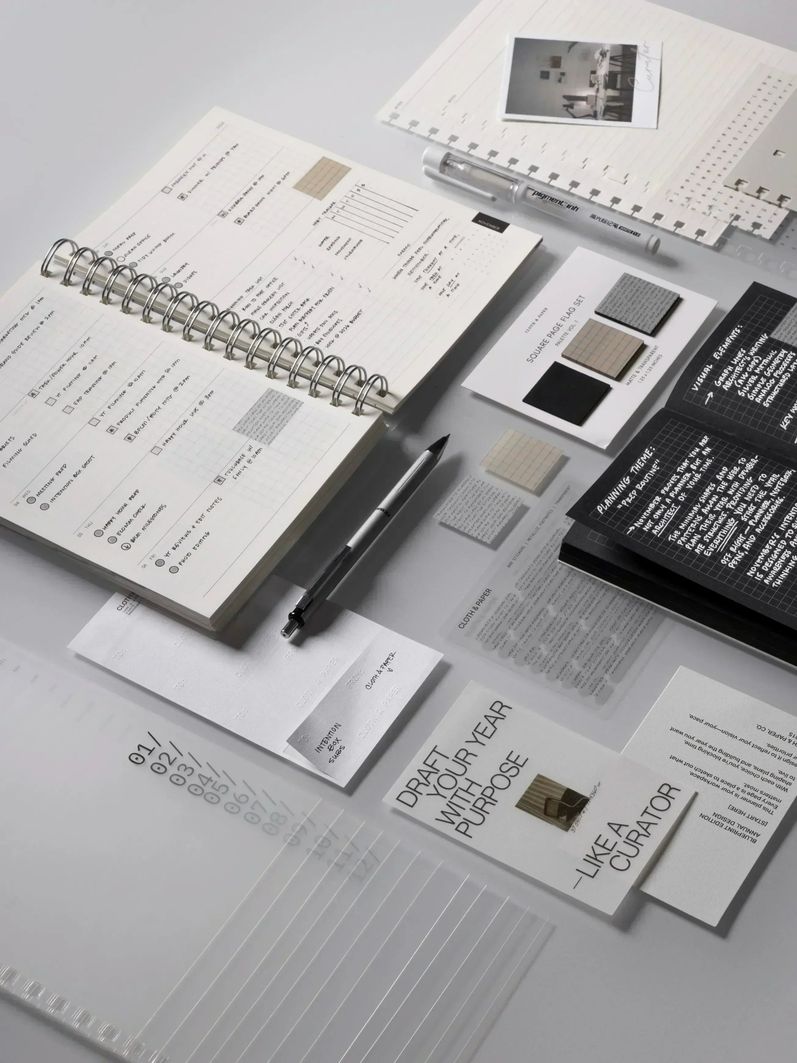 Flat lay of November 2025 Intention Box items on a white surface in neutral tones of black, white, and beige.