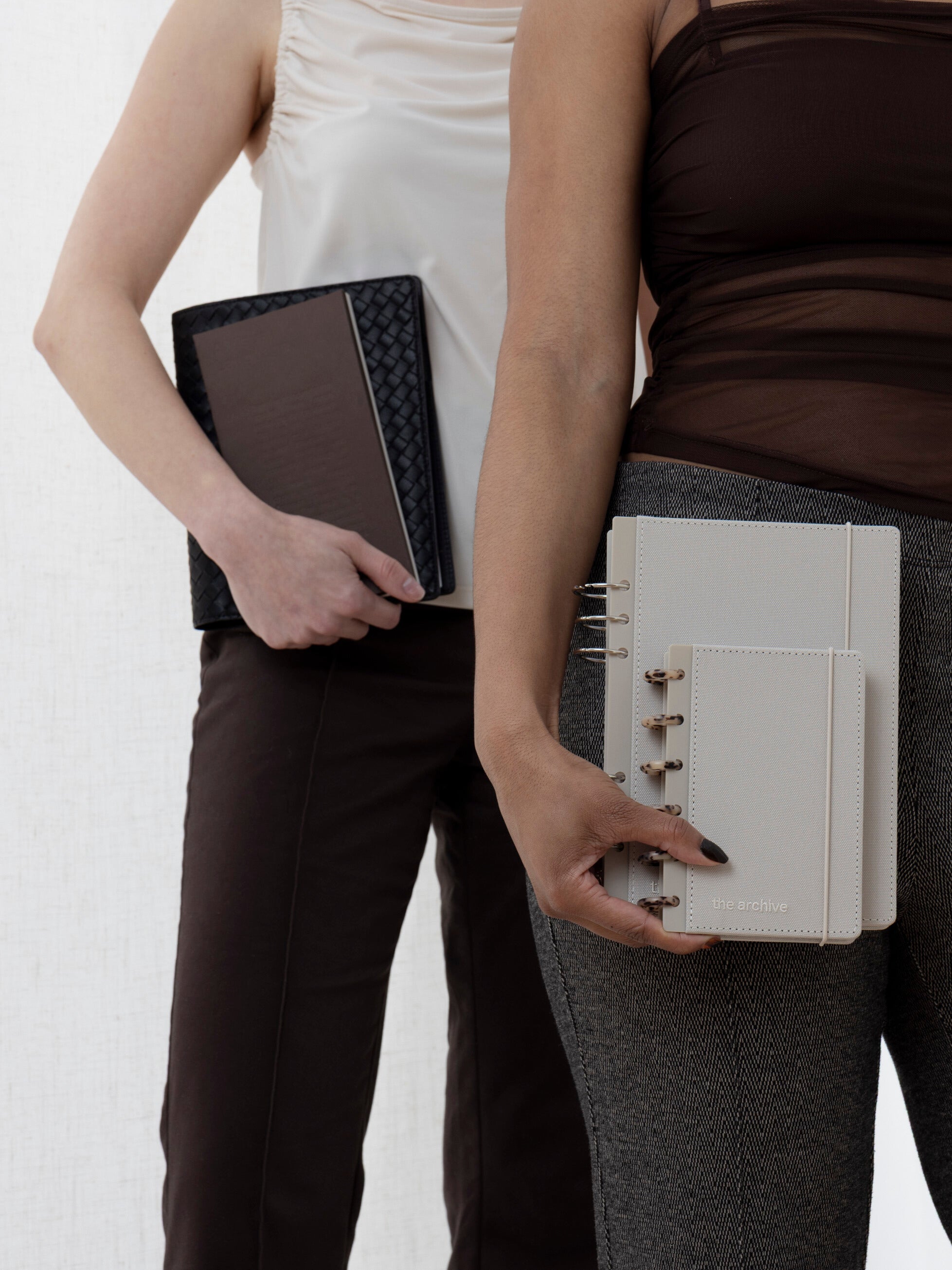 Two women hold planners with accessories from the Common Thread collection.