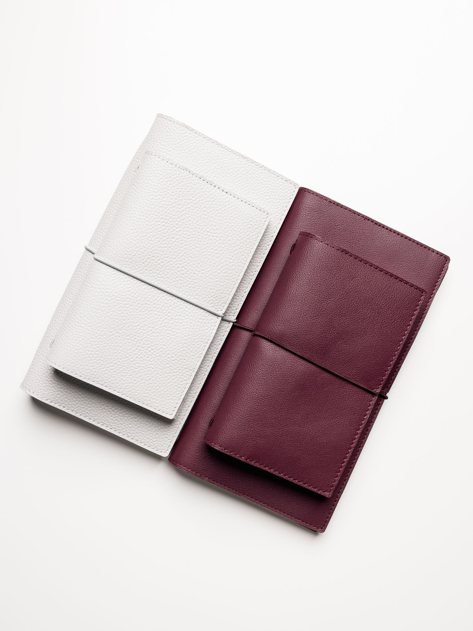 Red and grey genuine leather travel notebook covers shown with Pocket Plus size on top of A5 Slim size.