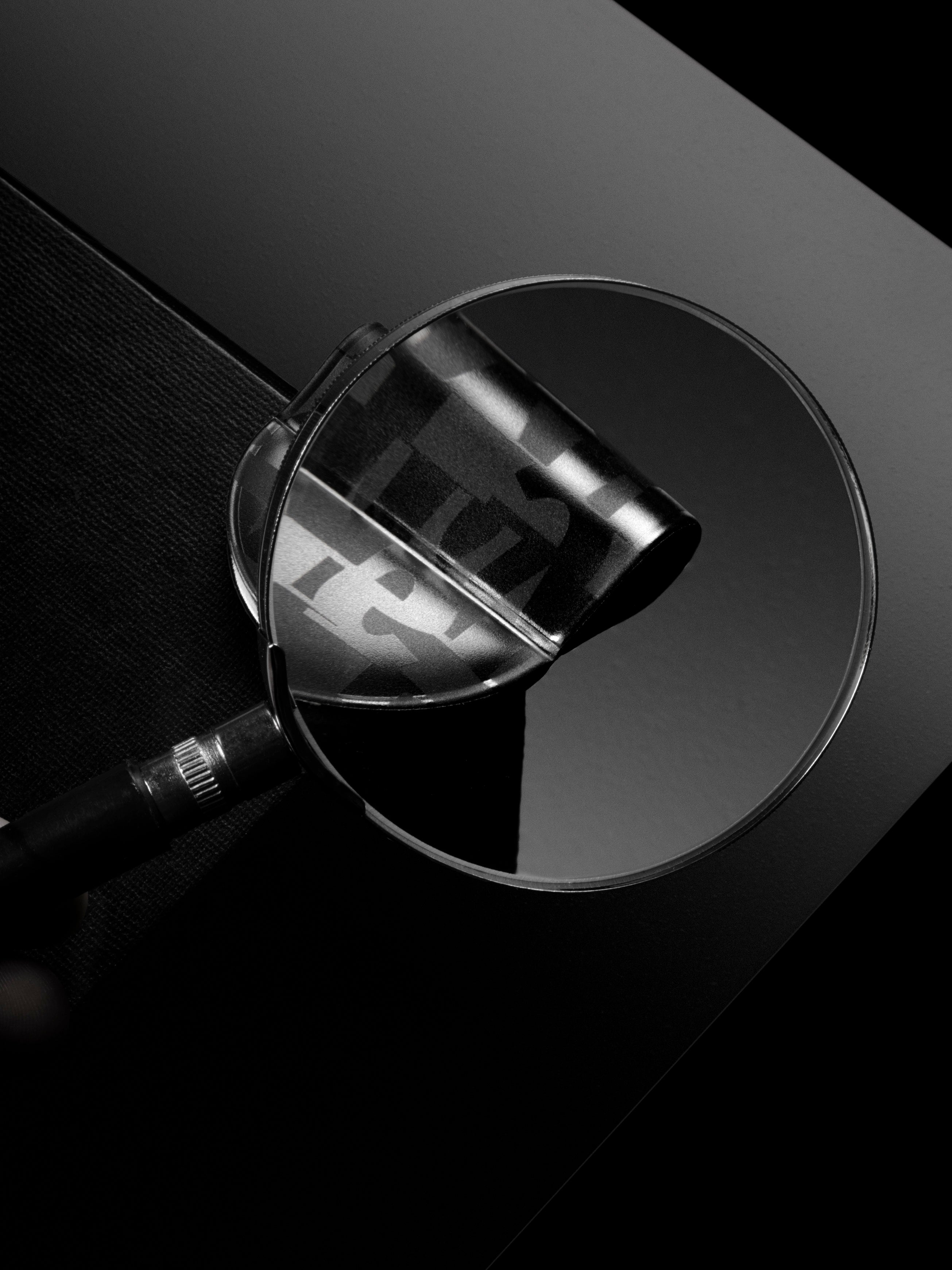 Magnifying glass examining the magnetic bookmark pen holder in the pattern torn magazine