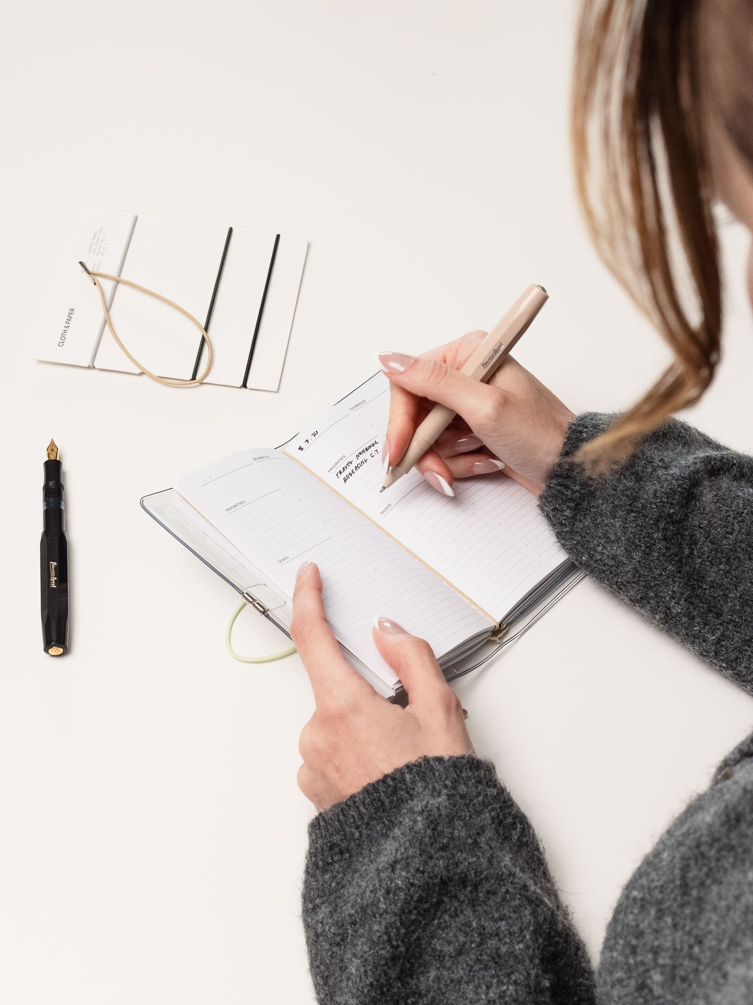 Woman writing in a pocket plus sized travel notebook.