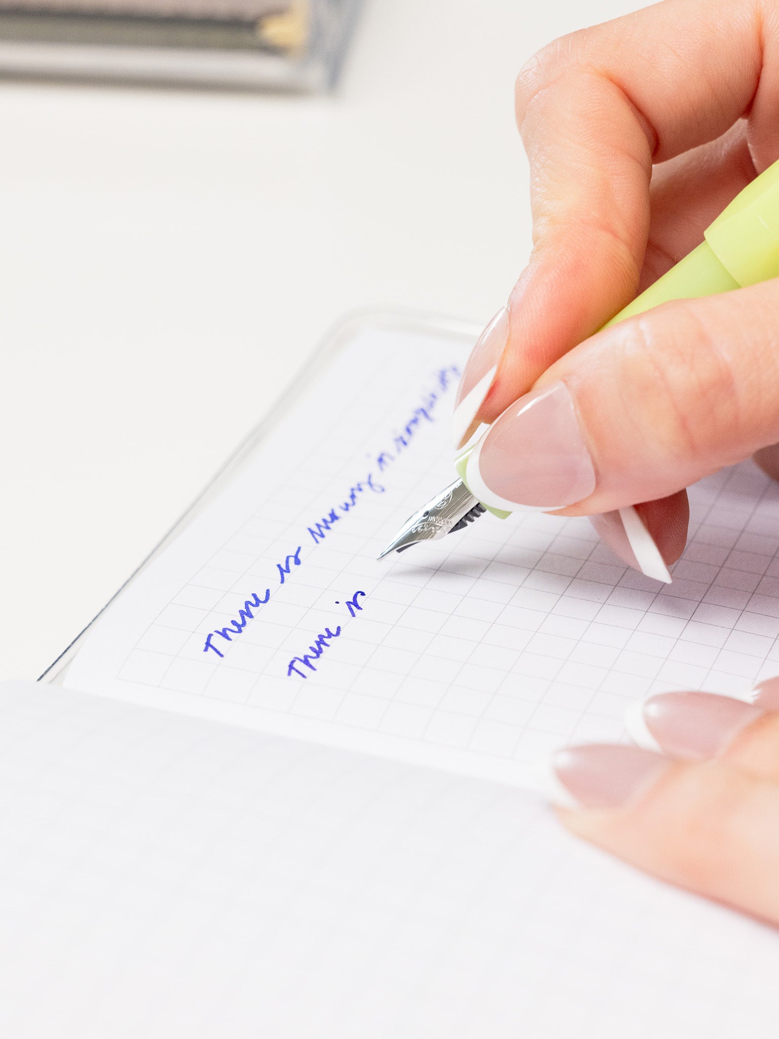 Hand writing with a lime green fountain pen.