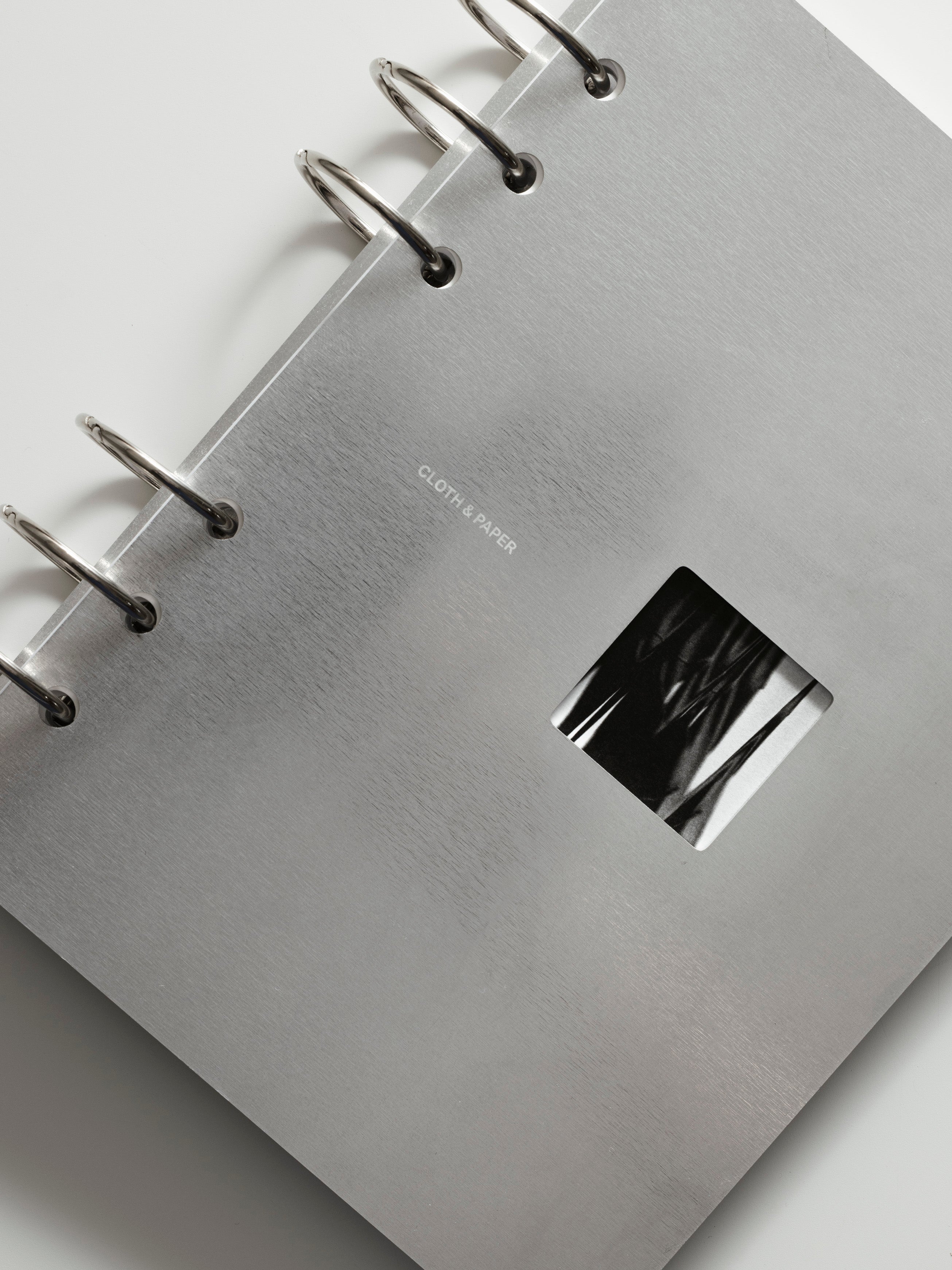 Silver ringbound notebook with a metallic cover on a light gray background