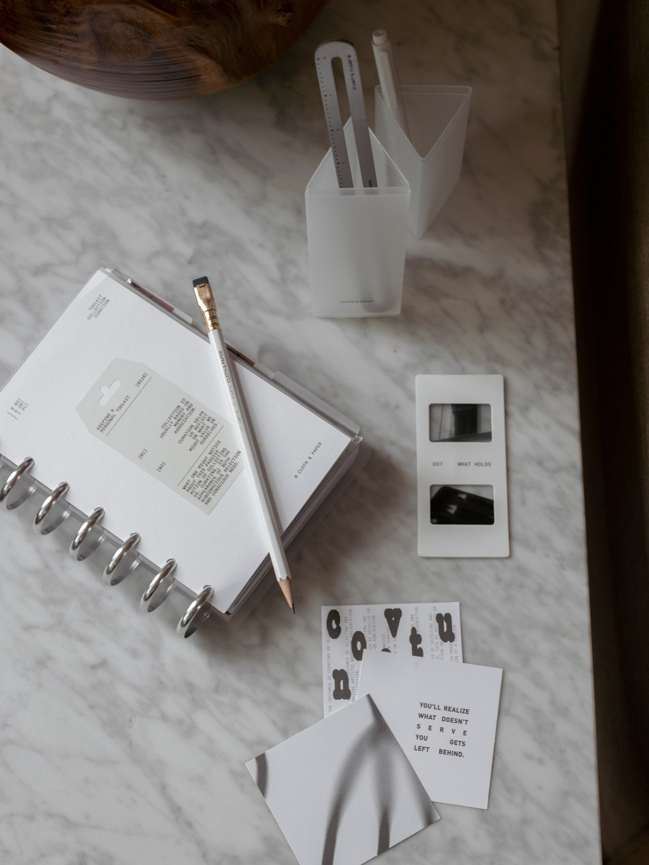 Overhead view of a Personal Wide Clad Cover Set, frosted Pencil Box, stainless steel ruler, photo slides, journaling cards, and punched sticker sheet arranged on a marble surface