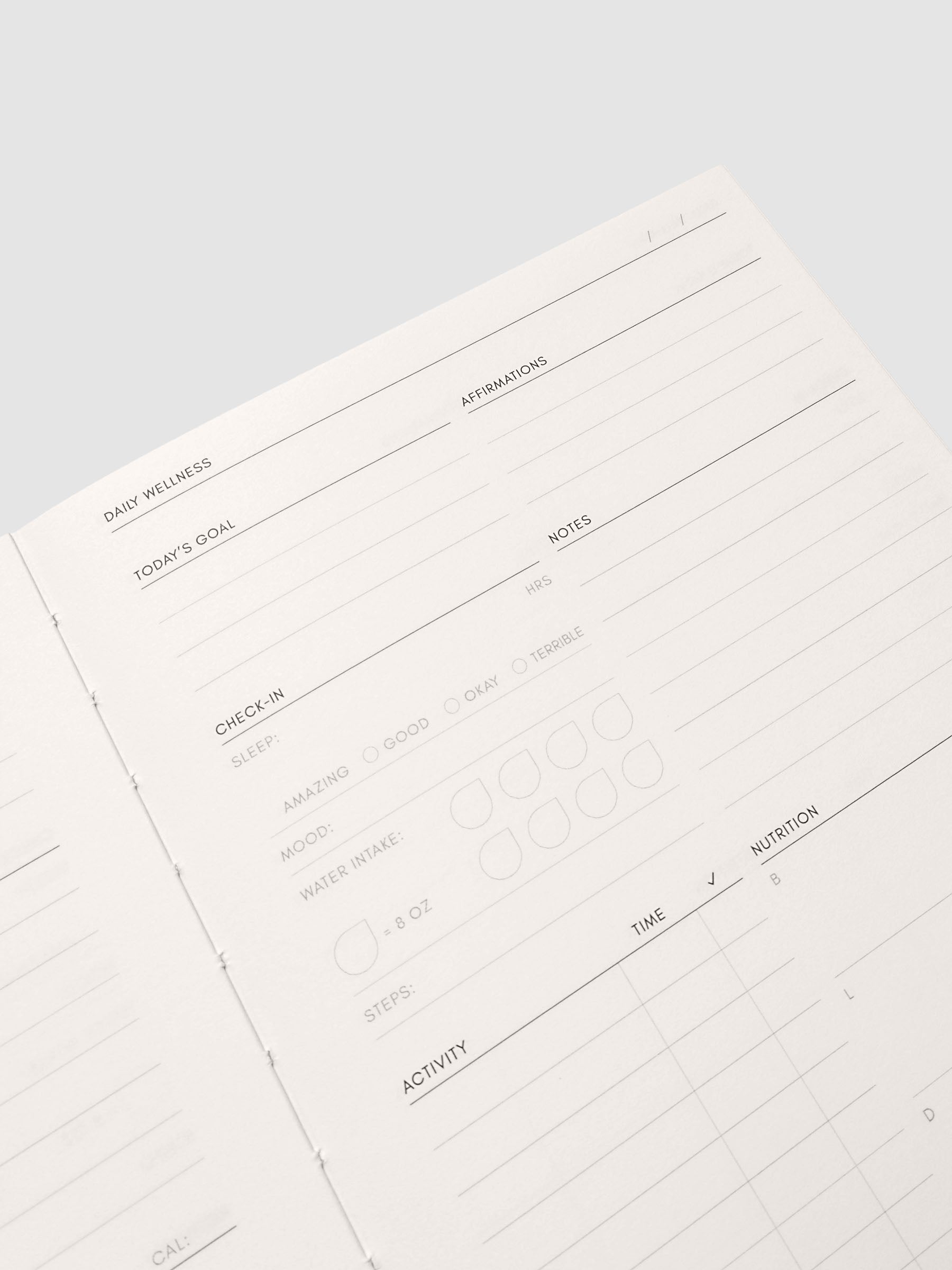 Close up of the Perfect Bound Notebook | A5 | Daily Wellness pages at an angle, showing headed sections and ruled lines