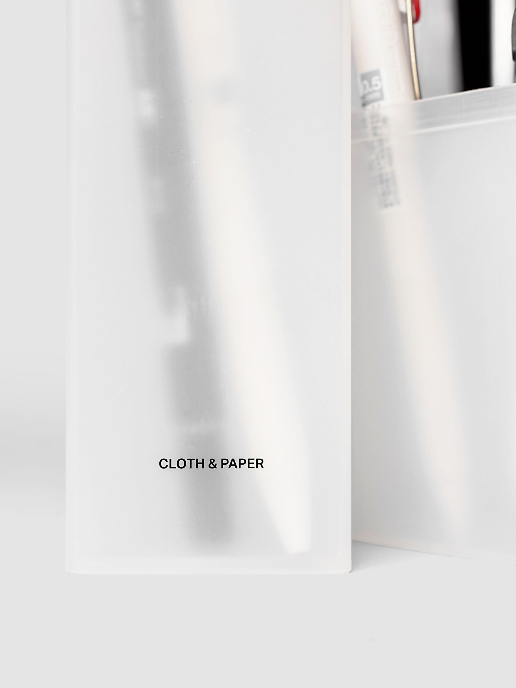 Pencil Box | Frosted, a triangular frosted plastic pencil case with a black logo on a light gray background
