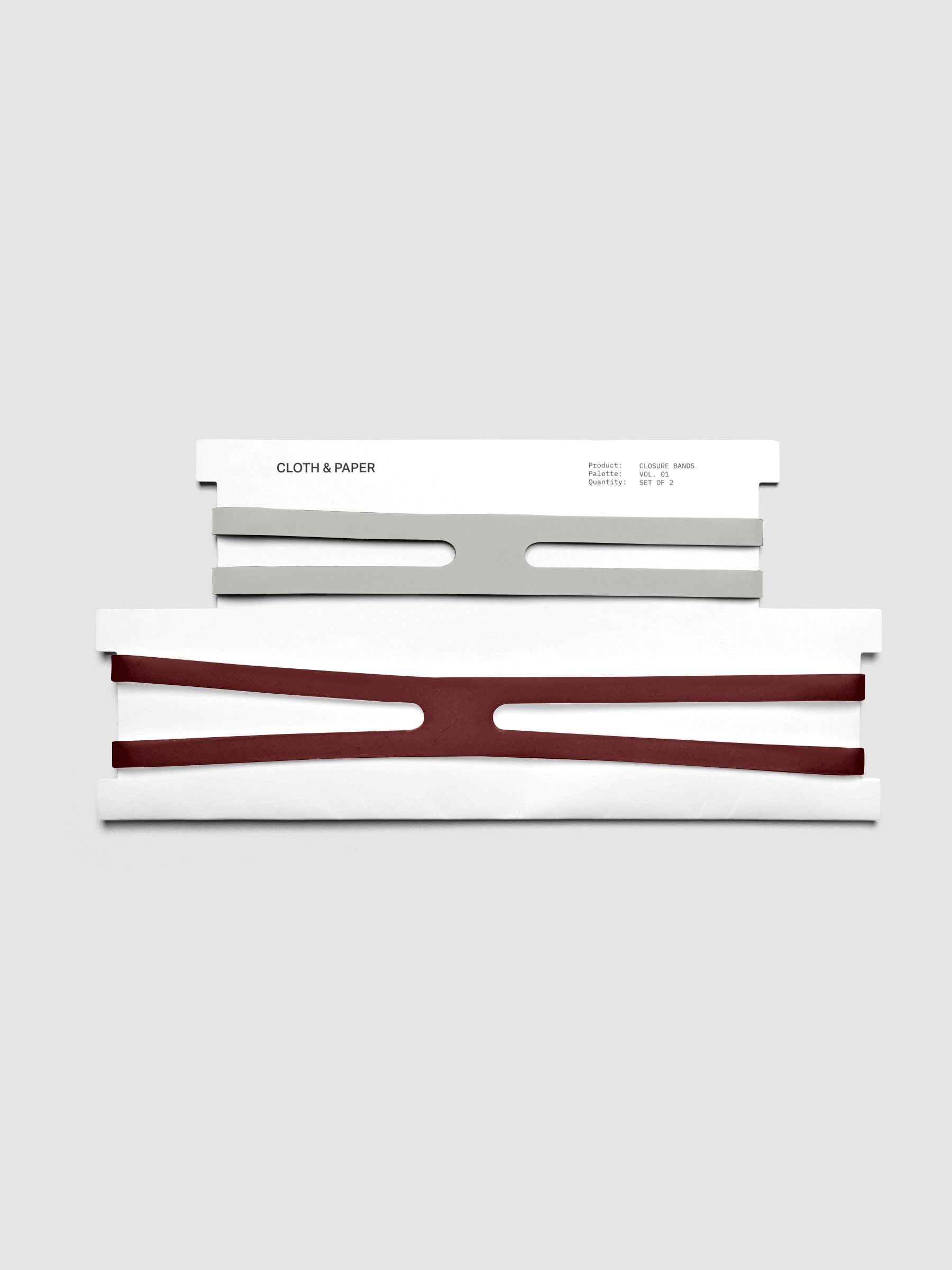 Ash and Bordeaux planner closure bands shown on their packaging cards, small ash band above and large bordeaux band below.