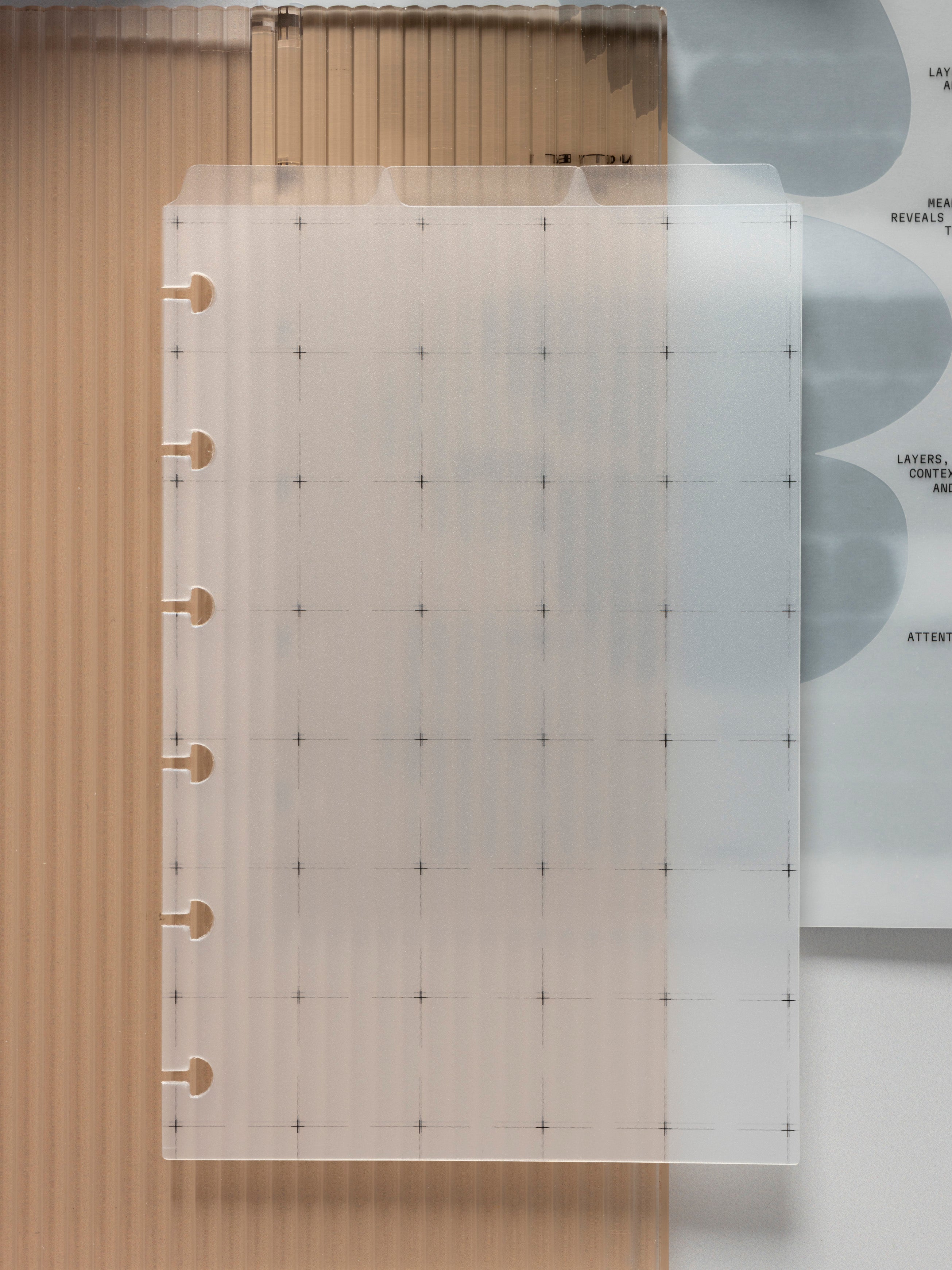 Frosted grid dashboard with top tabs, six ring punched, layered over an amber corrugated divider