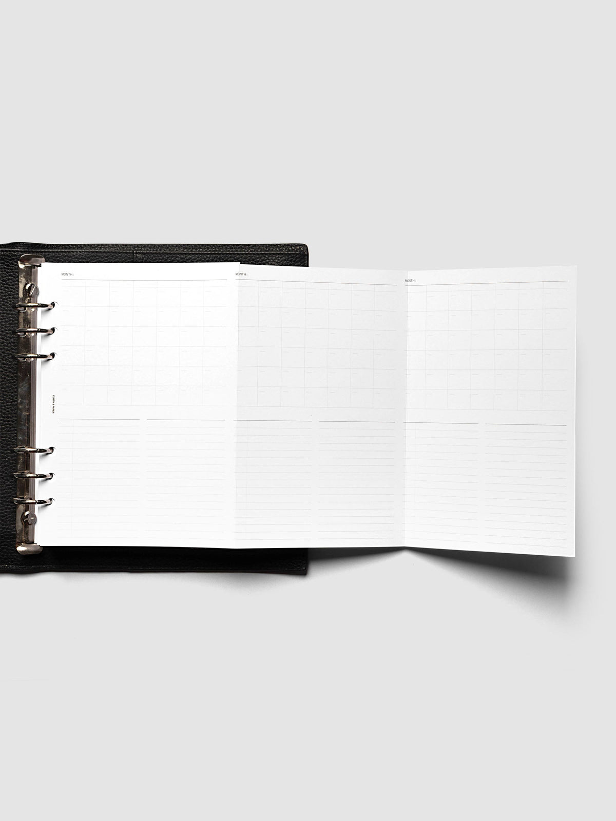 Monthly Fold Out Planner Insert Set of 2, A5 6-Ring Punch, the insert unfolded to the right of a black leather ring bound planner with silver rings, extending three monthly panels past the cover