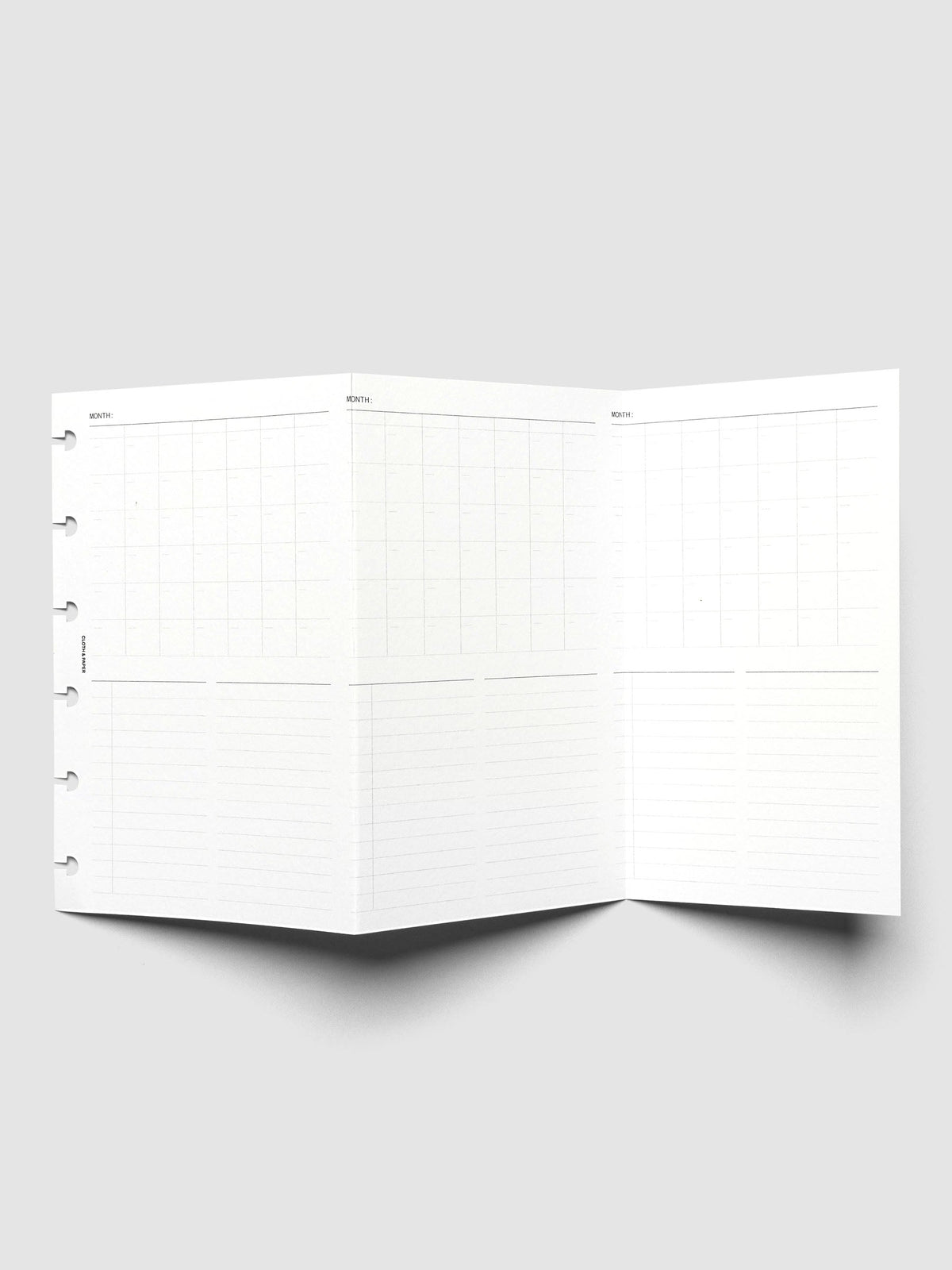 Monthly Fold Out Planner Insert Set of 2, CP Petite 6-Disc Punch, the insert unfolded and standing open, three monthly grids running across the panels above lined columns