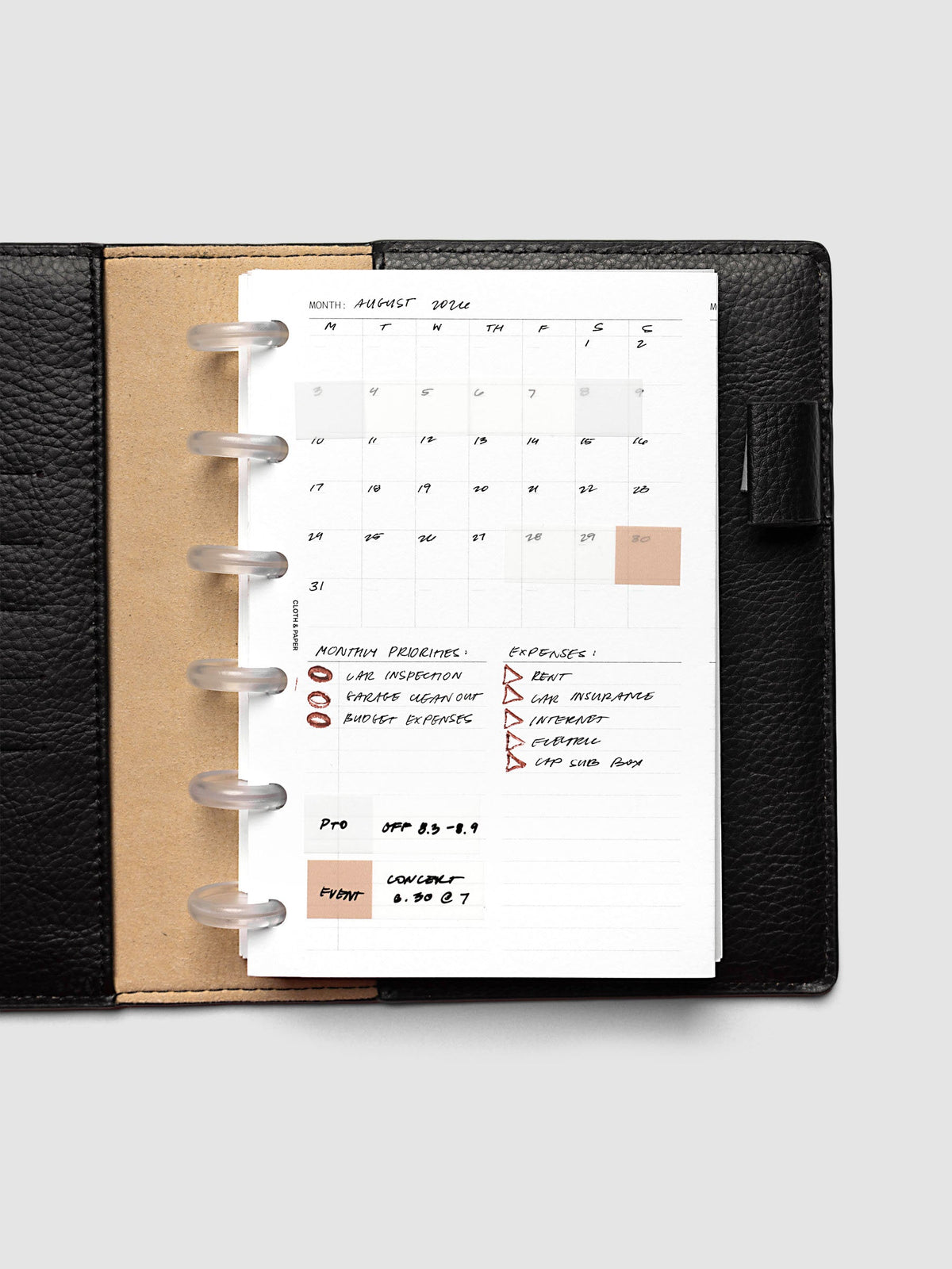 Monthly Fold Out Planner Insert Set of 2, CP Petite 6-Disc Punch, the insert filled in by hand for August in a black leather discbound planner, with peach and clear highlight blocks marking dates and black ink lists below