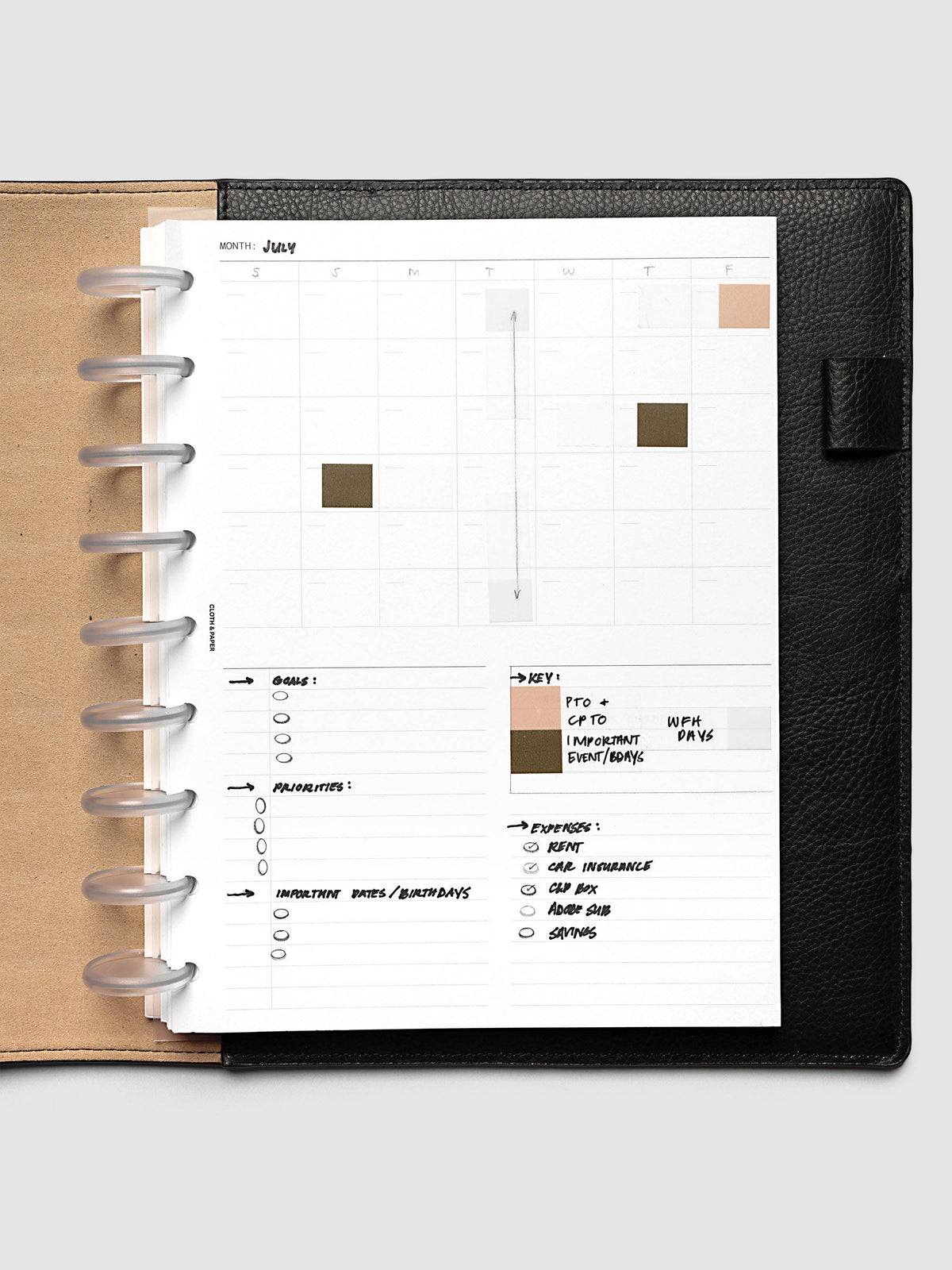 Monthly Fold Out Planner Insert Set of 2, HP Classic 9-Disc Punch, the insert filled in by hand for July in a black leather discbound planner, with peach and olive blocks keyed to time off and events and black ink goals and expenses lists below