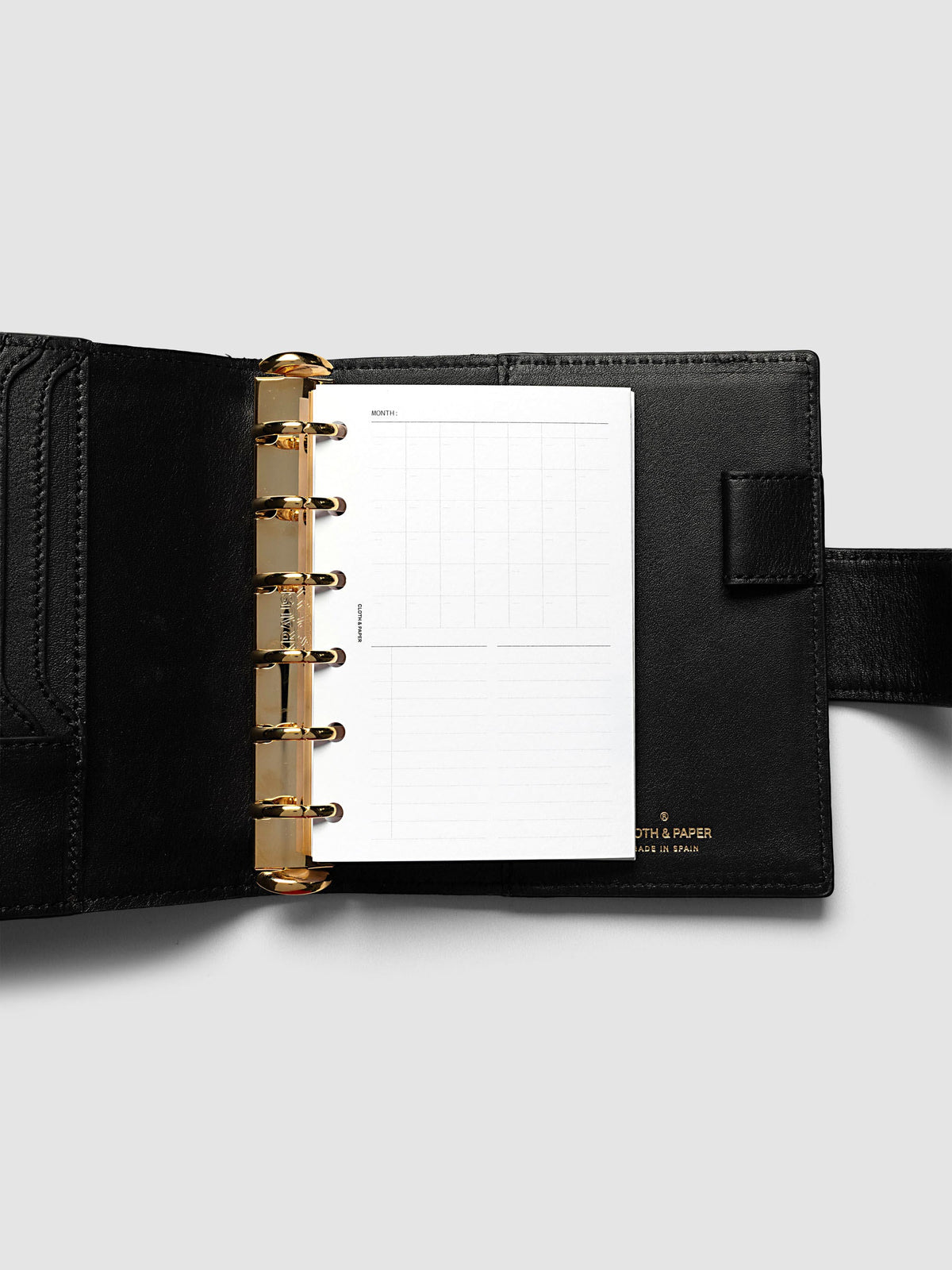 Monthly Fold Out Planner Insert Set of 2, Pocket 6-Ring Punch, the insert folded closed in a small black leather ring bound planner with gold rings, card slots and gold foil branding on the cover
