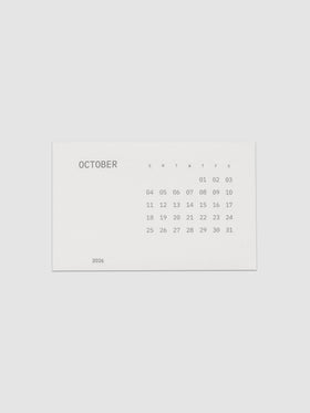 Pocket Calendar | October 2026, a small off white card printed in soft gray with the month name at the left, a full grid of dates under single letter weekday headers, and the year set at the lower left