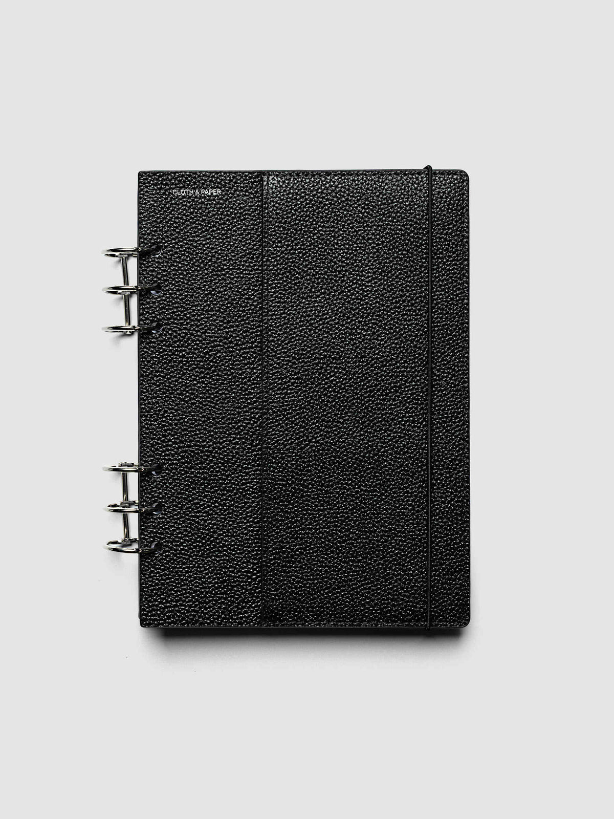 The A5 6-Ring Punch Genuine Leather Planner Cover Set closed on a ring bound planner, showing the silver rings, the silver foiled logo, and the bungee cord holding the stack shut