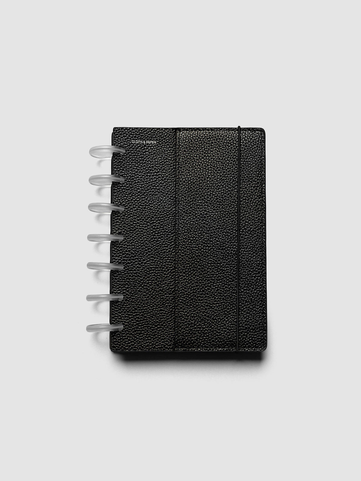 The HP Mini Genuine Leather Planner Cover Set closed on a ring bound planner, showing the silver rings, the silver foiled logo, and the bungee cord holding the stack shut