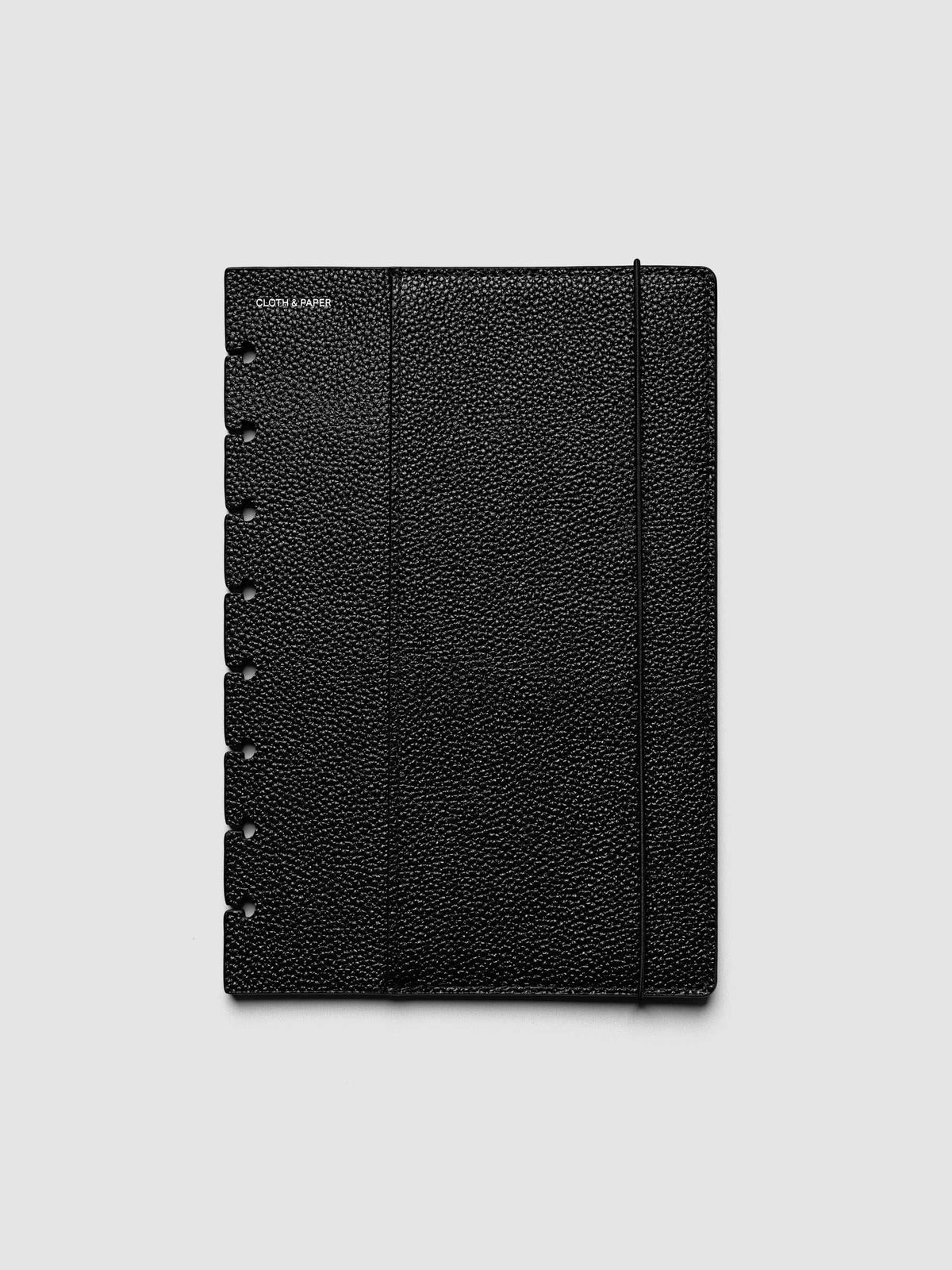 The front cover of the Half Letter 8-Disc Punch Genuine Leather Planner Cover Set laid flat, showing pebbled black leather, the silver foiled logo at the top left, the punch holes down the left edge, and the bungee cord running down the right