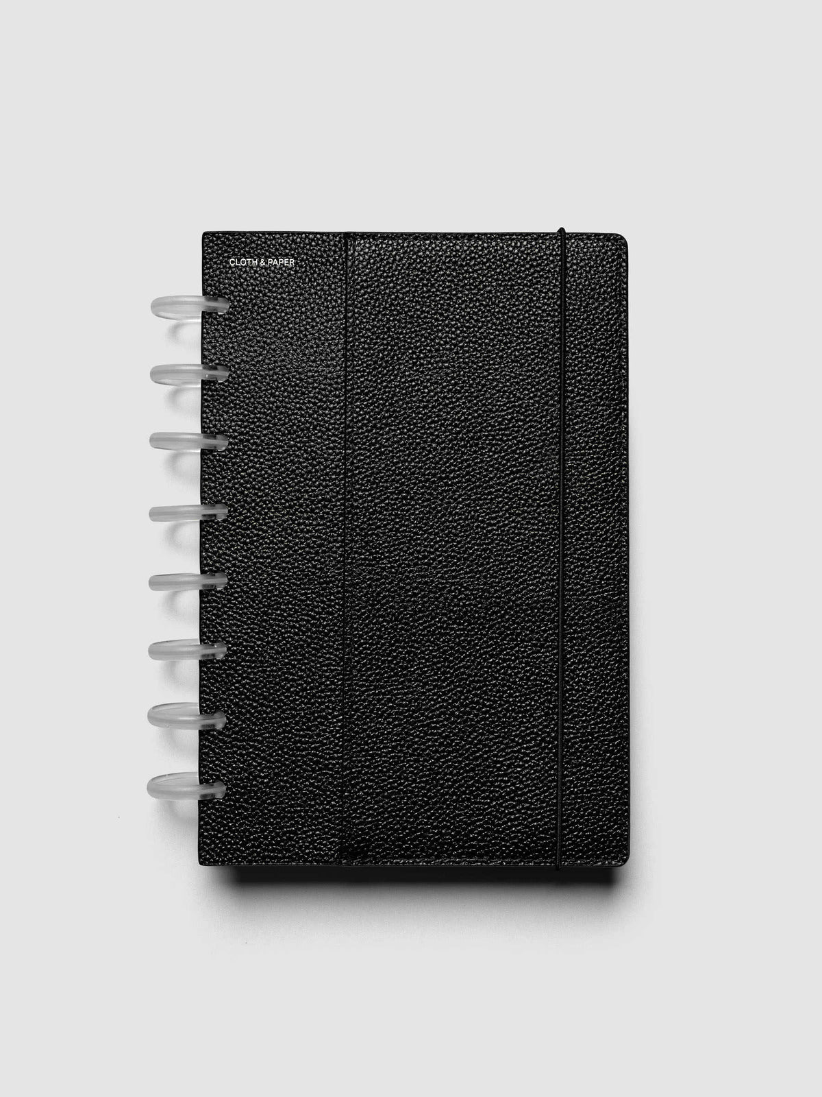 The Half Letter 8-Disc Punch Genuine Leather Planner Cover Set closed on a ring bound planner, showing the silver rings, the silver foiled logo, and the bungee cord holding the stack shut