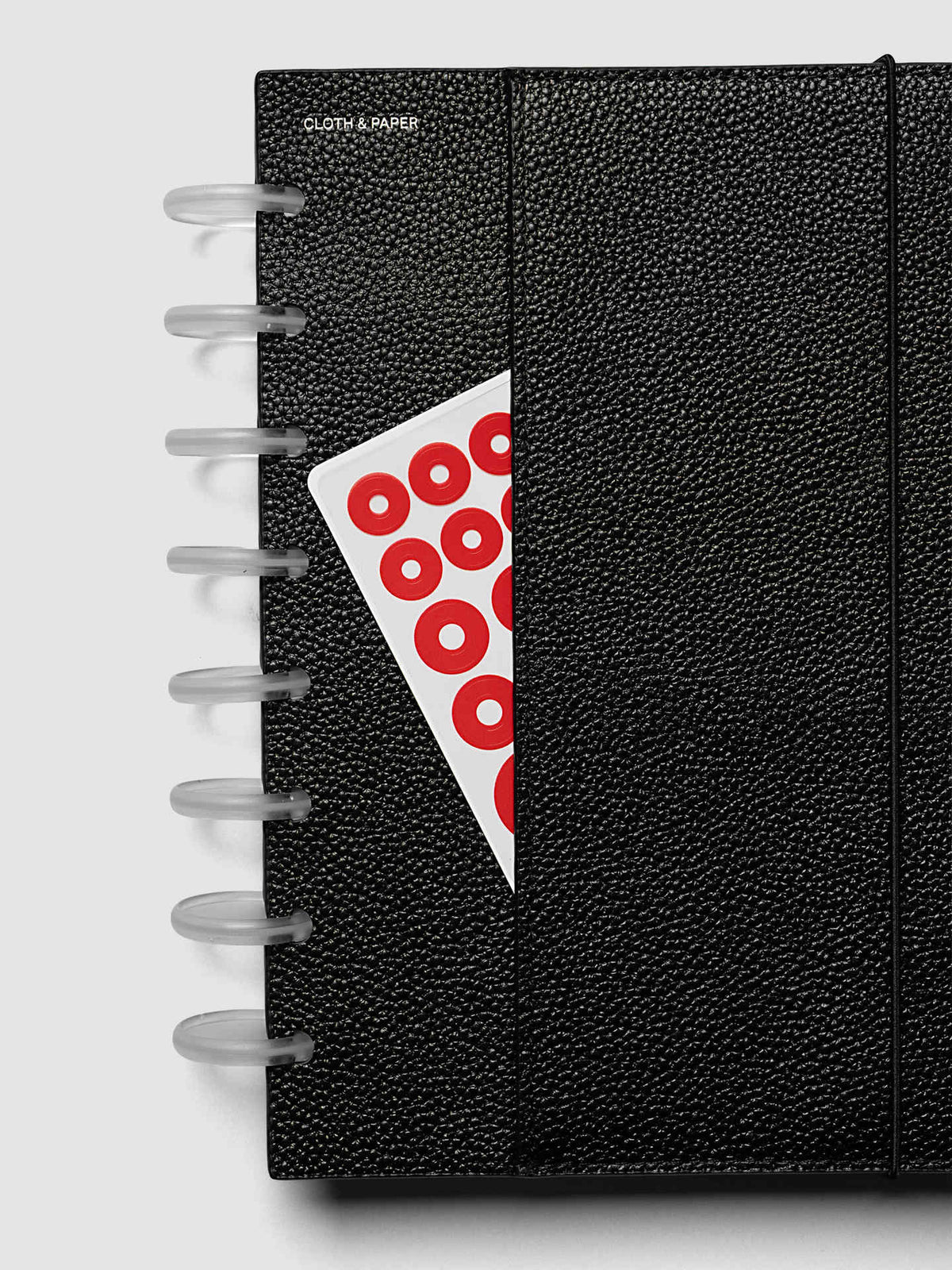 Close-up of the corner of the Half Letter 8-Disc Punch Genuine Leather Planner Cover Set with the bungee cord running along the edge of the pebbled black leather