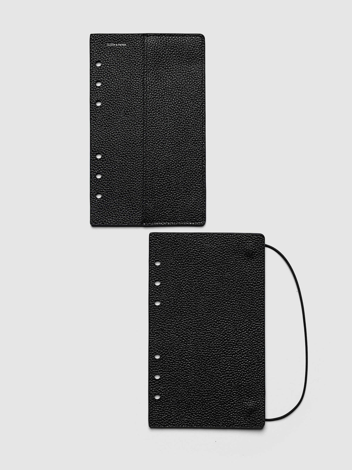 Both covers of the Personal Genuine Leather Planner Cover Set laid flat side by side, the front cover with its sewn pocket seam and the back cover with the bungee cord looping out from the edge