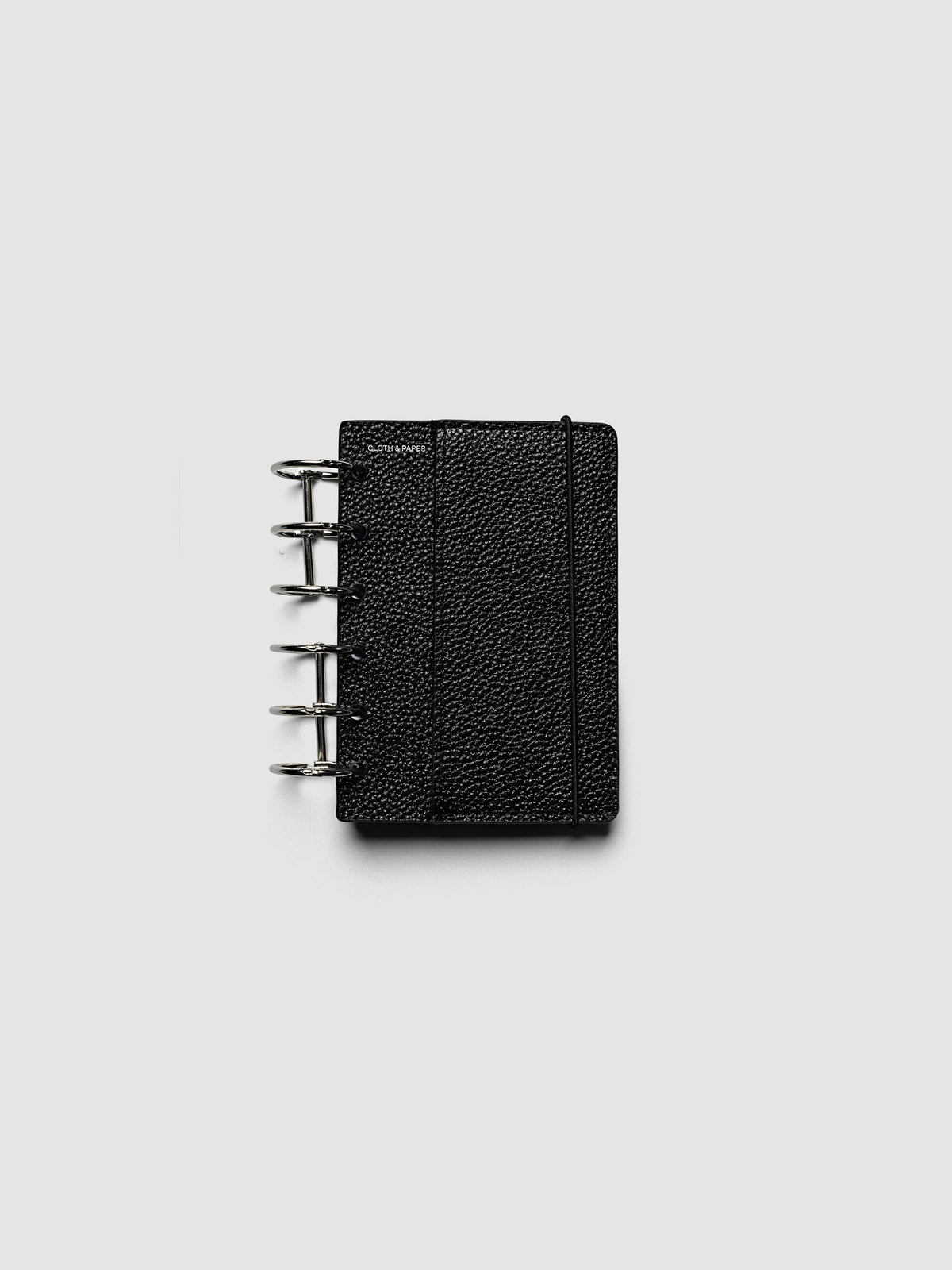 The Pocket Genuine Leather Planner Cover Set closed on a ring bound planner, showing the silver rings, the silver foiled logo, and the bungee cord holding the stack shut