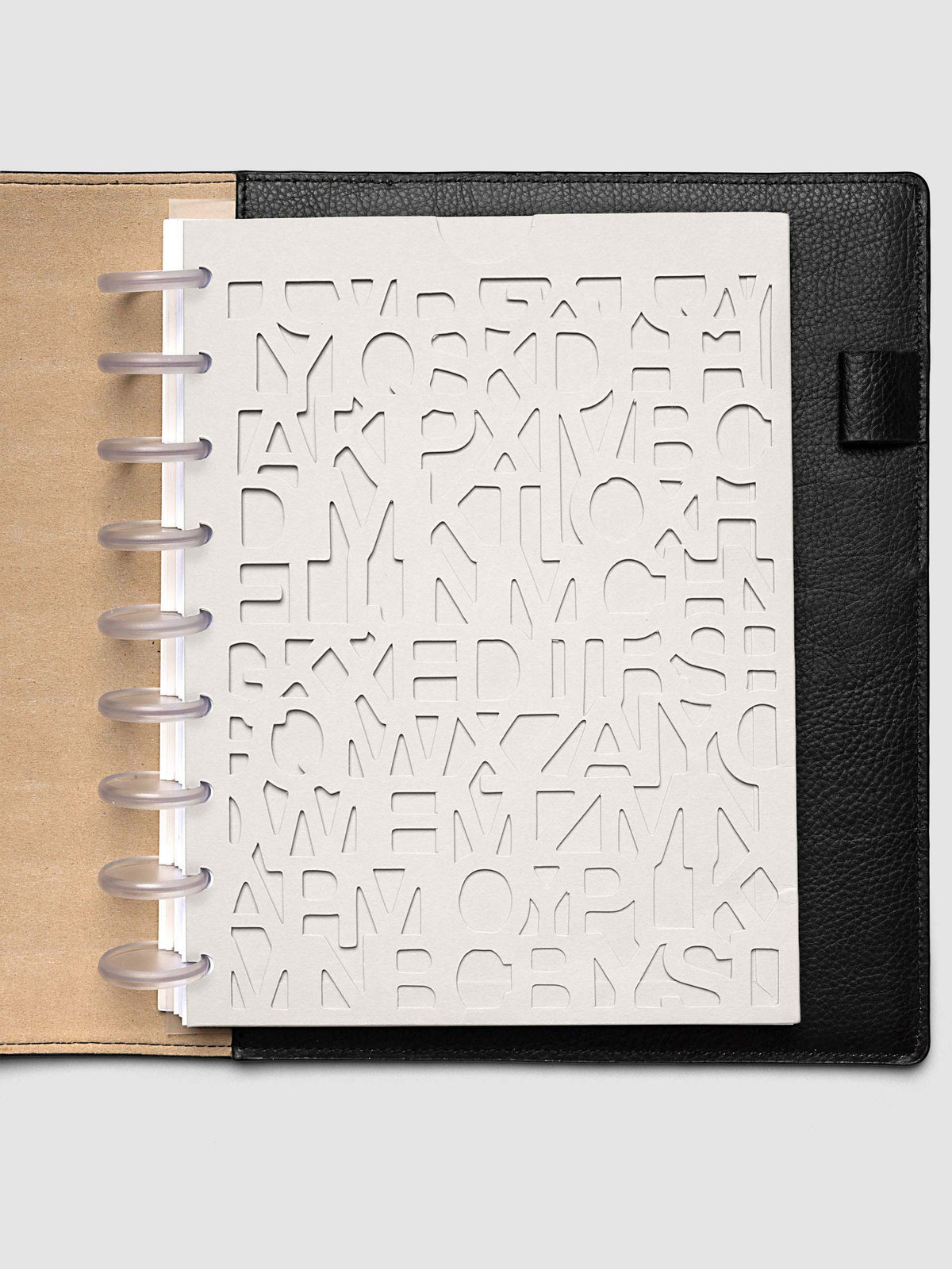 The HP Classic 9-Disc Punch Diecut Pocket Folder empty at the front of a black leather ring bound planner, the cut letters showing the blank page beneath