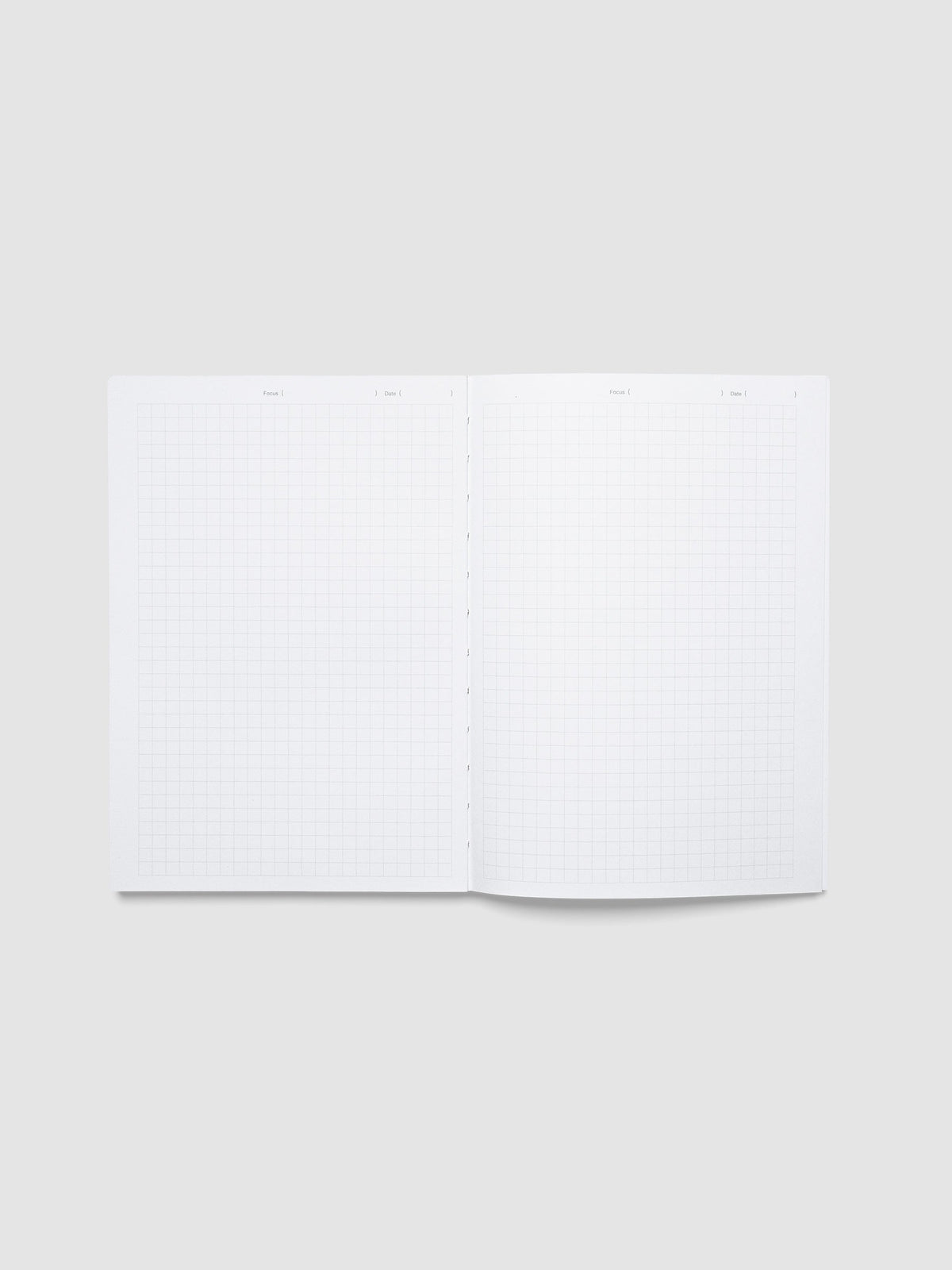 The Precision Notebook | A5 open flat to a graph paper spread, with a Focus and Date line across the top of each page