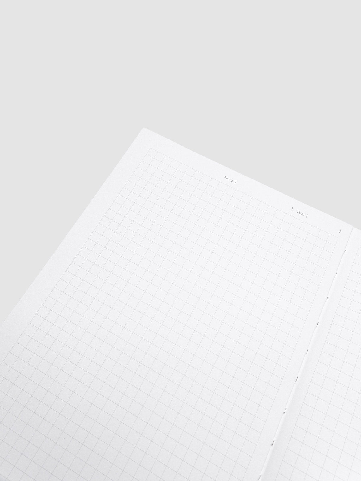 Close-up of a single graph paper page in the Precision Notebook | A5, showing the Focus and Date line and the stitching along the gutter