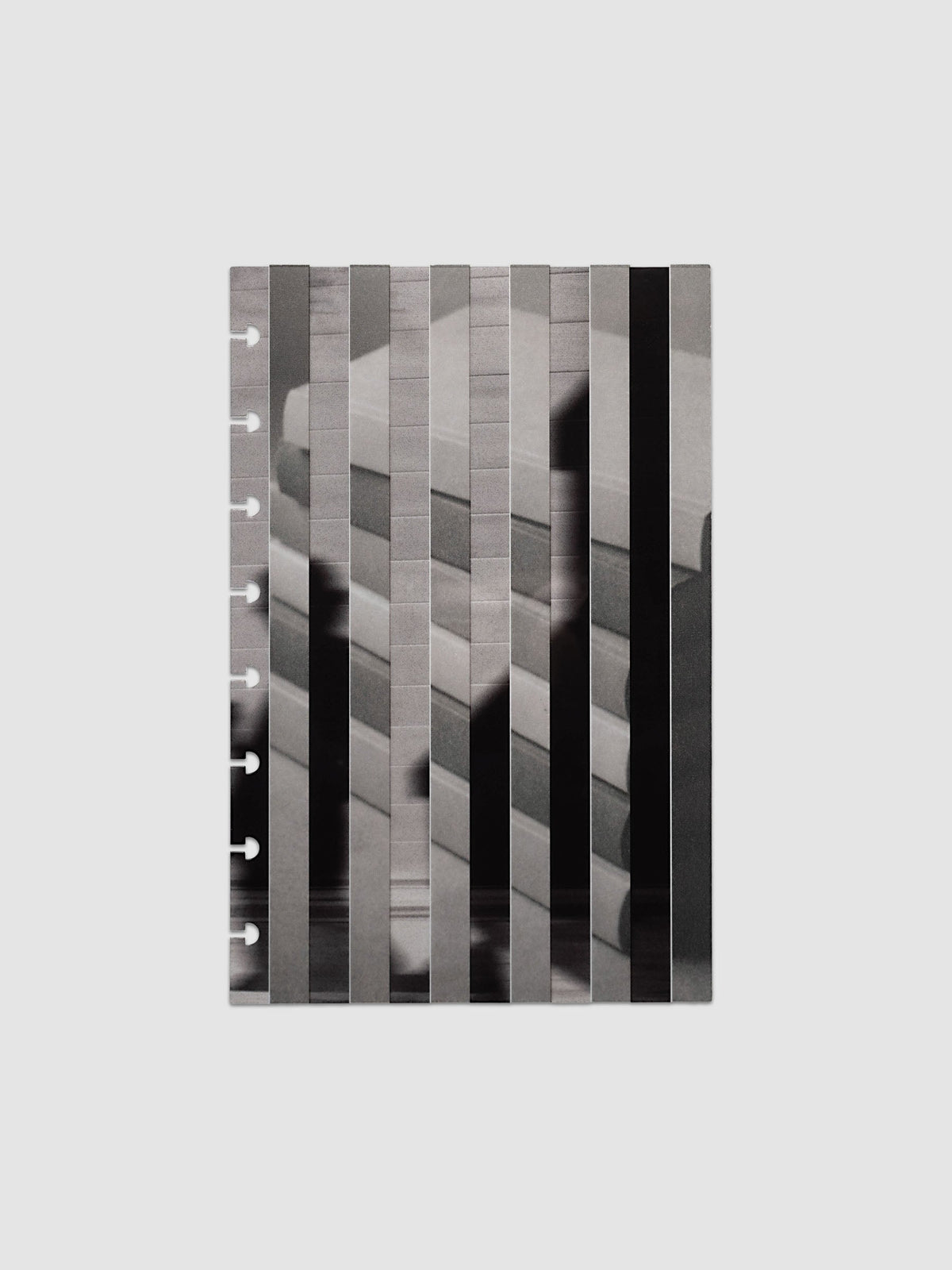 The vellum base layer of the Half Letter 8-Disc Punch Strips Planner Dashboard Duo laid flat, showing a greyscale photograph of a stack of books sliced into vertical strips and offset