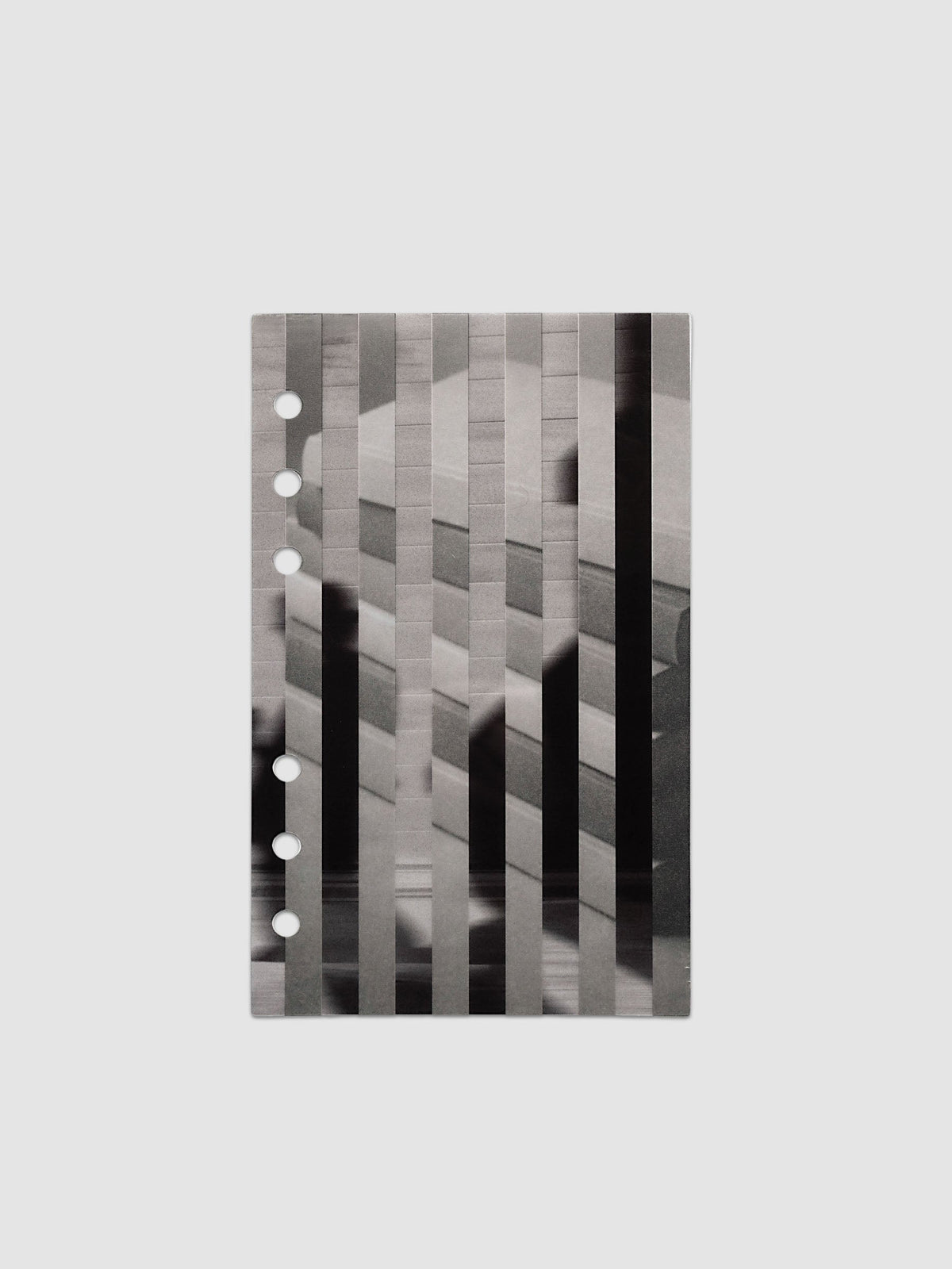 The vellum base layer of the Personal Strips Planner Dashboard Duo laid flat, showing a greyscale photograph of a stack of books sliced into vertical strips and offset