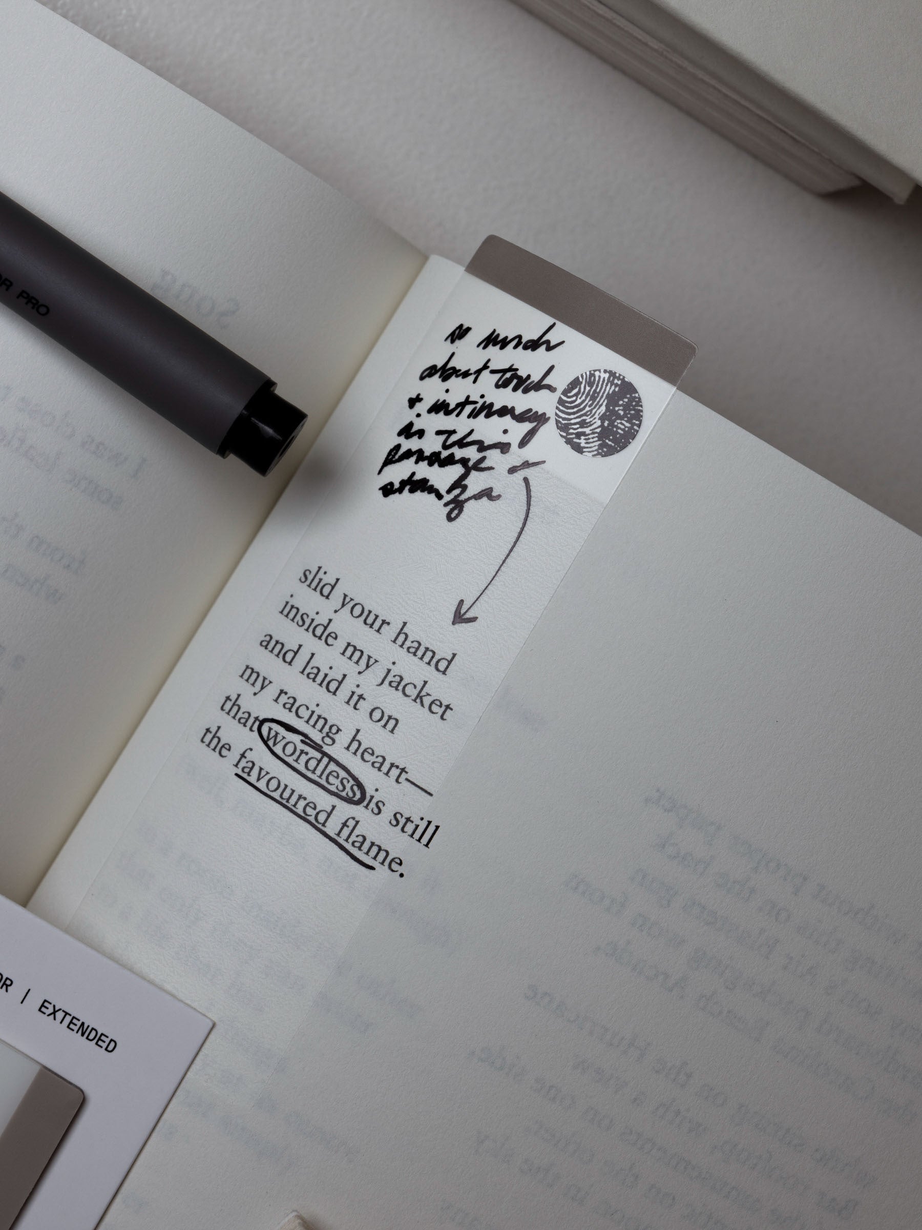 Extended page flag affixed to an open book page with handwritten notes.