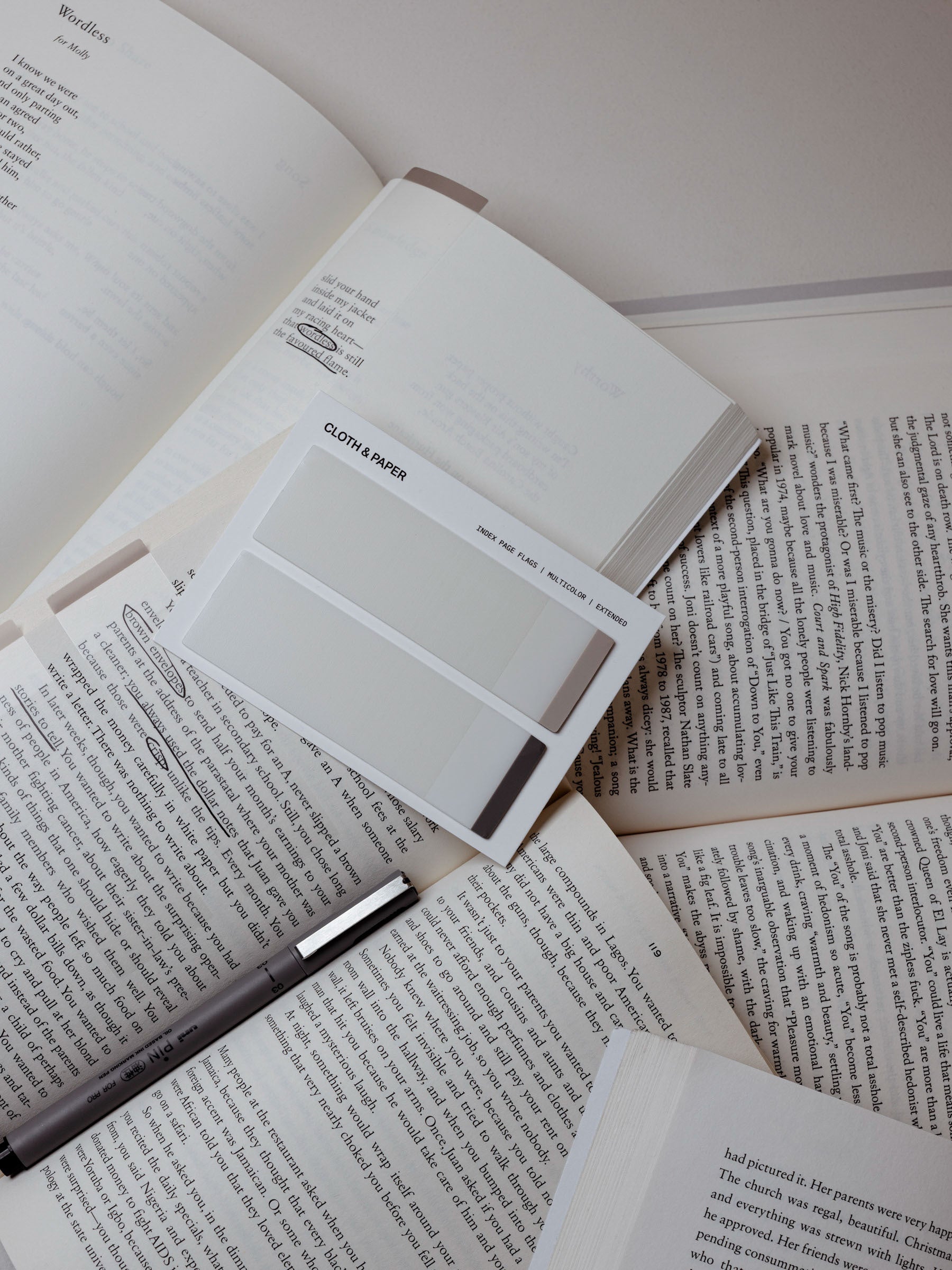 Set of extended page flags in two colors resting on top of a pile of open books.
