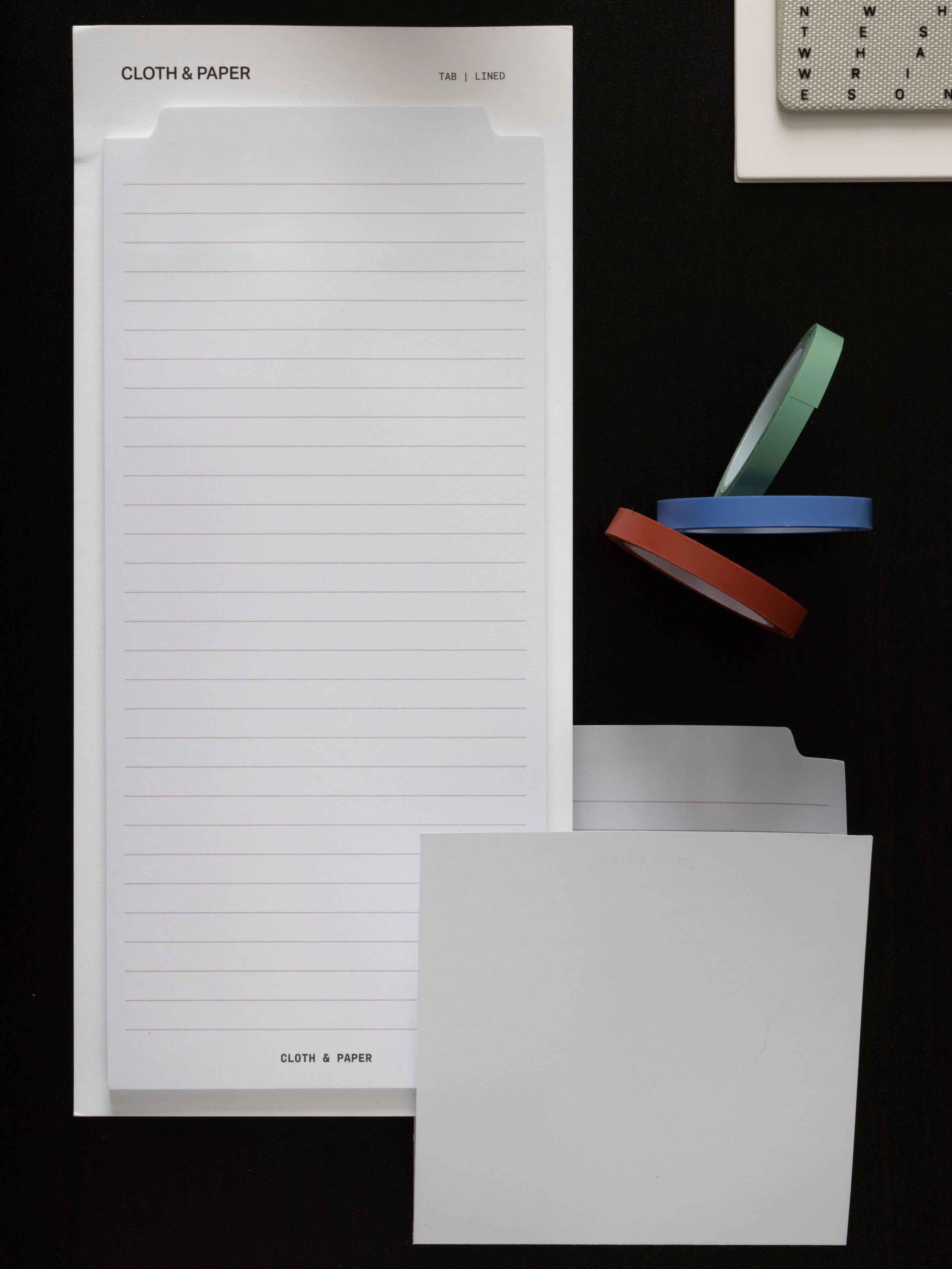 Large Sticky Notes in the tab lined layout on a black surface, shown with three rolls of Annotation Tape, a tab divider, and a Magnetic Bookmark at the top edge.