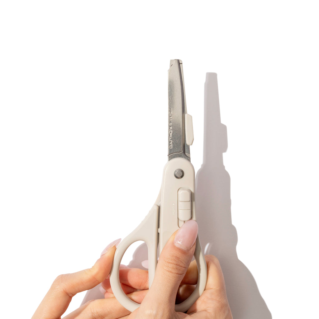 A pair of pale hands shown activating the scissors' cutting blade mode.