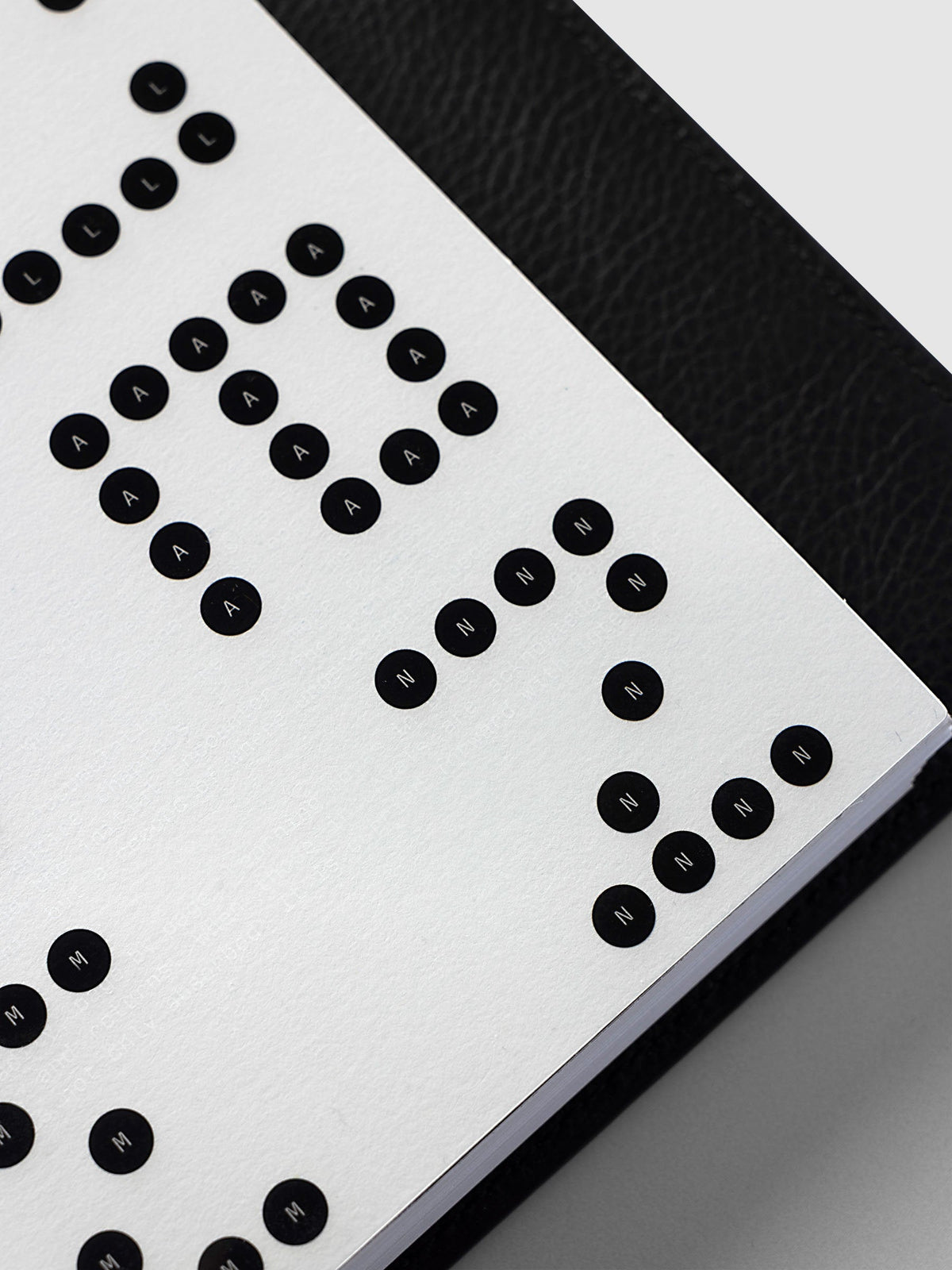 Scantron Dashboard Duo, Half Letter 8-Disc Punch, close-up of the lower corner of the pair against the black leather cover