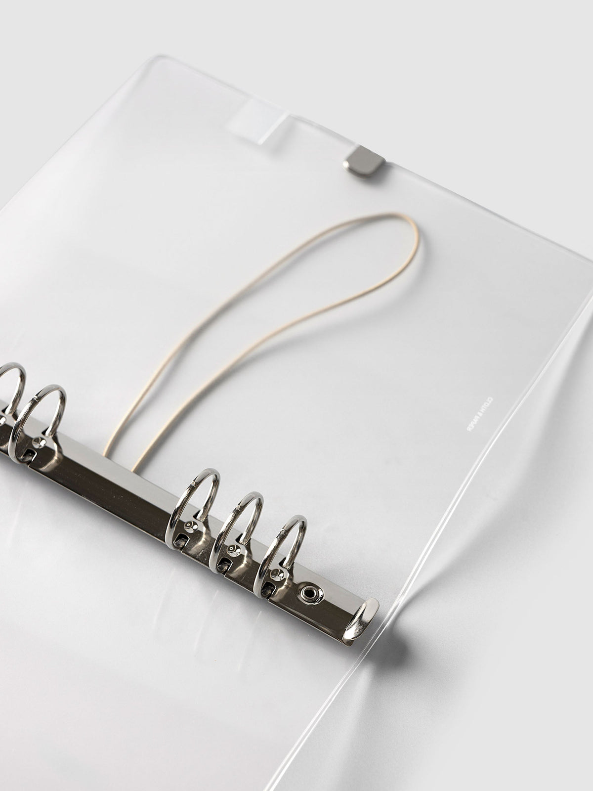 Angled close-up of the silver six-ring mechanism and beige bungee cord inside the A5 6-Ring Punch Ring Cover in frosted vinyl
