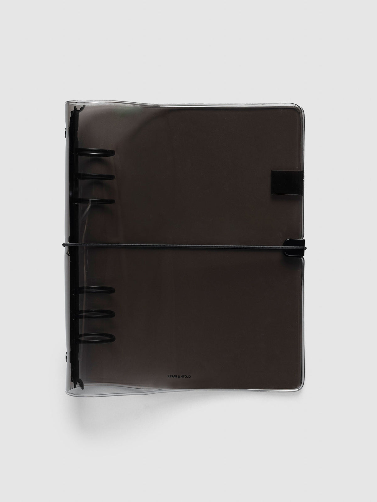 Ring Cover in black tinted vinyl, A5 6-Ring Punch, closed, with the black six-ring mechanism at the spine and a black bungee cord hooked to a black clip