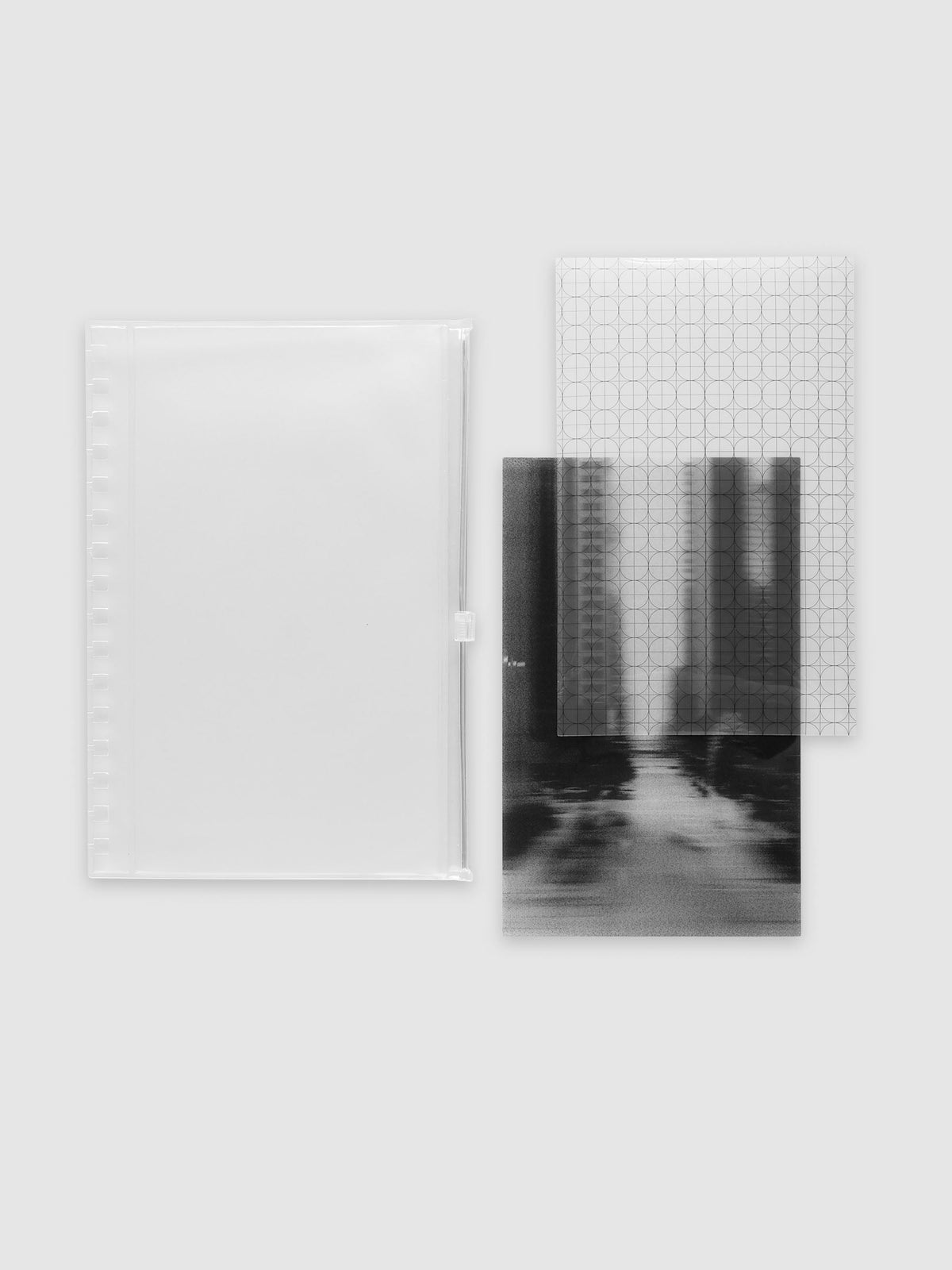 One frosted transparent zippered pouch, one clear circle and graph overlay and one black and white blurred photo insert laid side by side. Shown in size A5 Spiral.