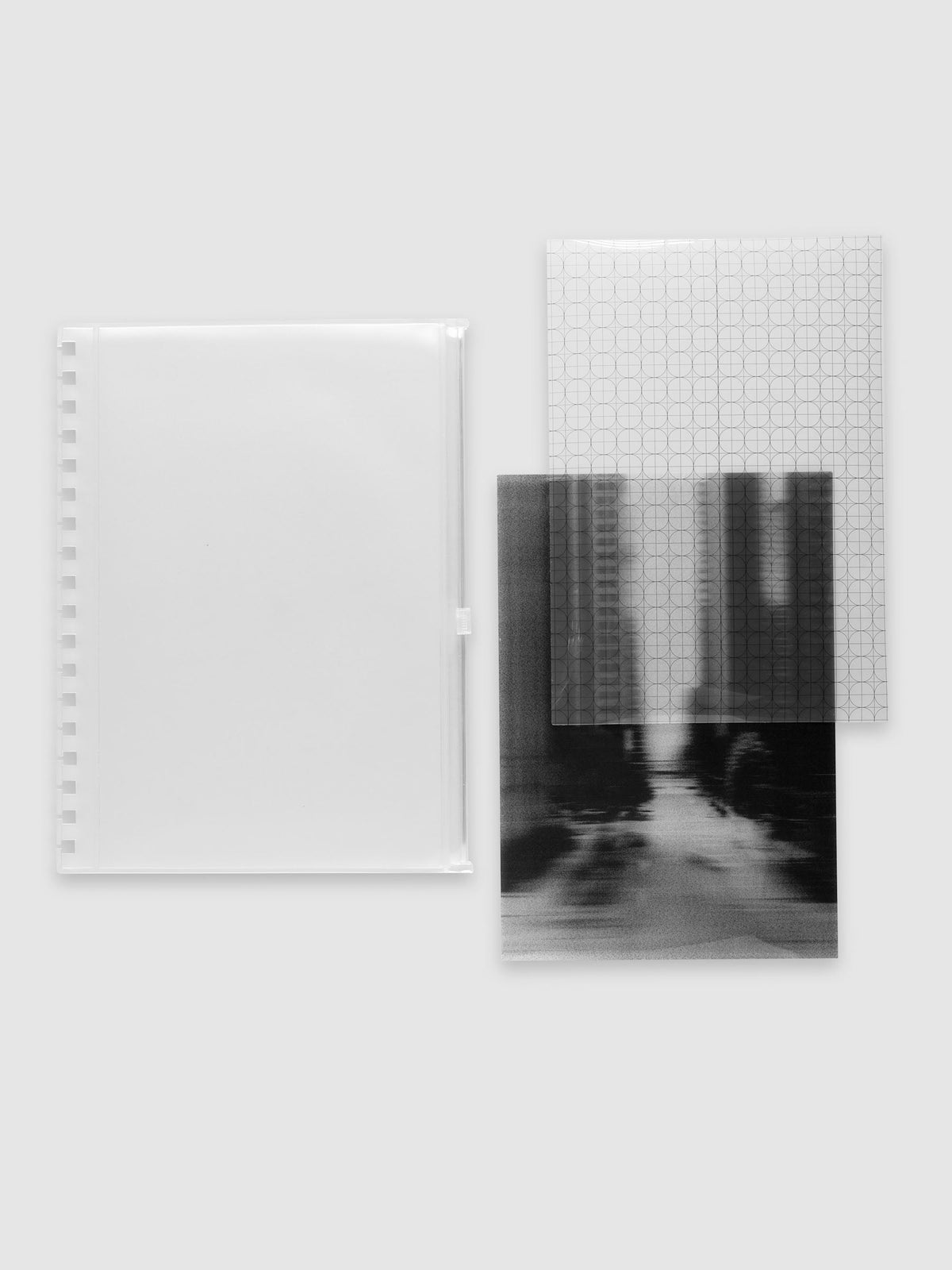 One frosted transparent zippered pouch, one clear circle and graph overlay and one black and white blurred photo insert laid side by side. Shown in size HP Classic Spiral.