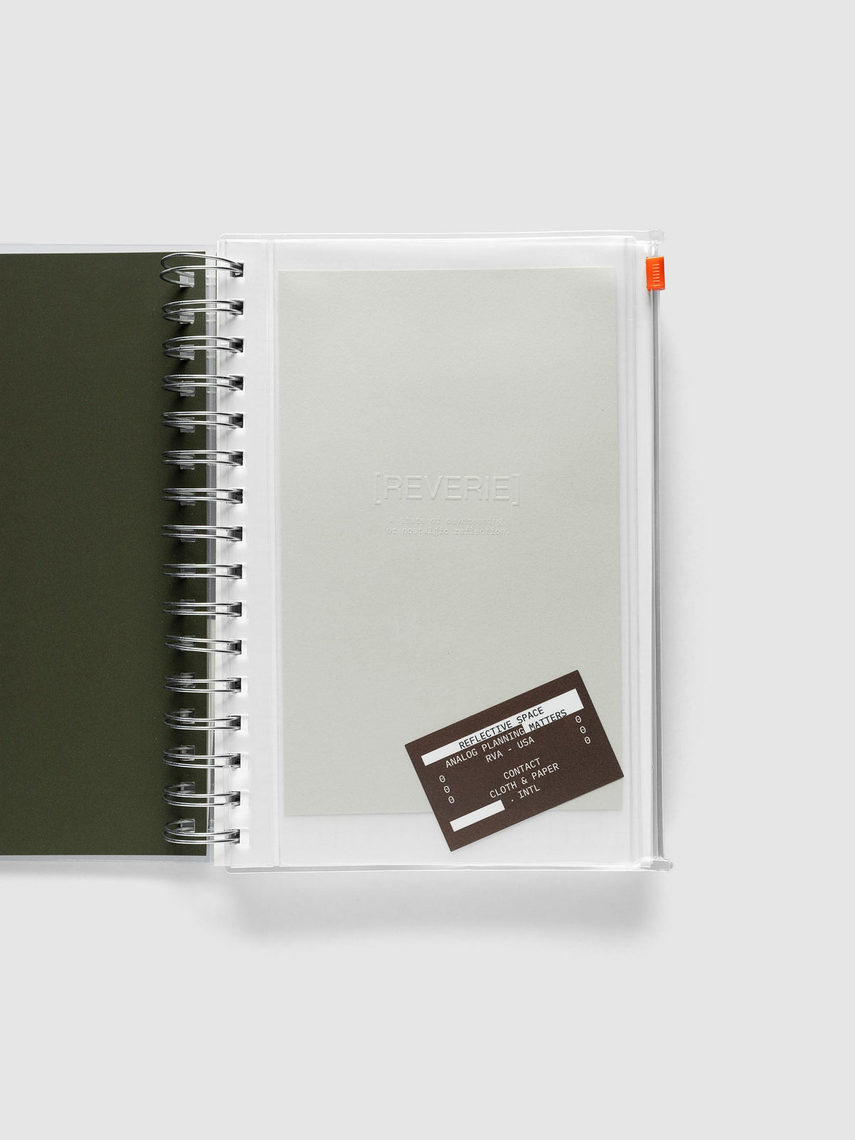Reverie Storage Holder bound into a spiral notebook in size A5 Spiral, with the light grey embossed dashboard and brown sticker inside the clear pouch.