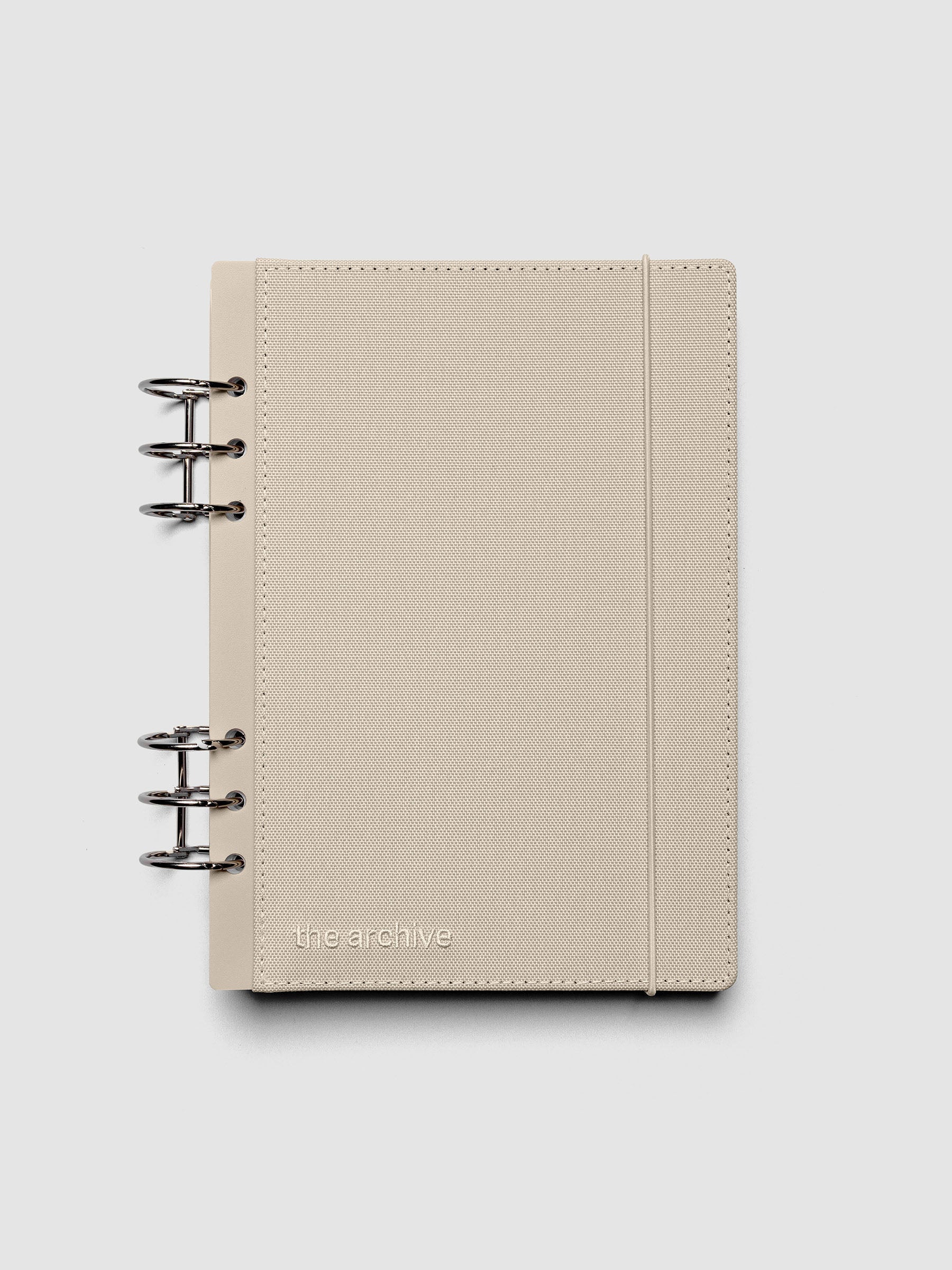 A5 ring bound planner with a beige bookcloth cover against a grey background.