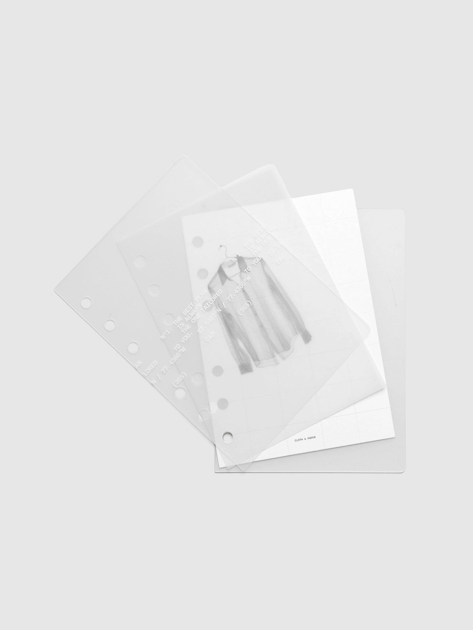 Transparent planner cover set with white printed text design and accompanying black and white dashboard with an image of a tailored shirt on a hanger shown offset. Pre-punched for 6-ring planners shown in size A6.