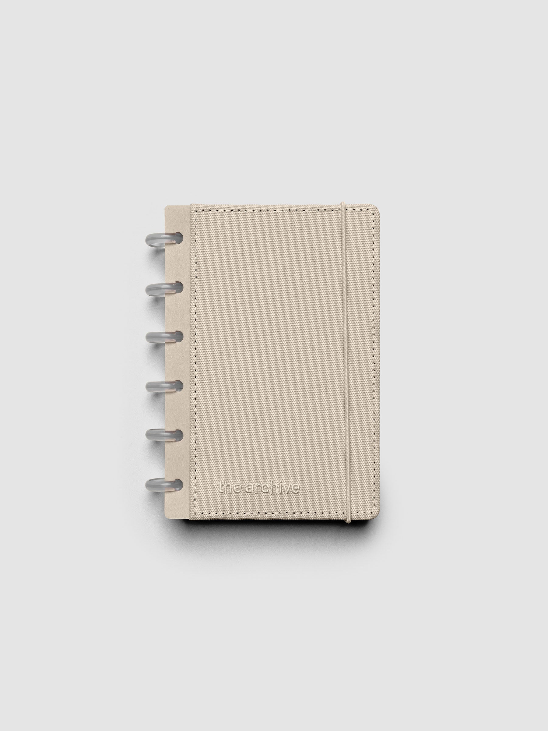 CP Petite discbound planner with a beige bookcloth cover against a grey background.
