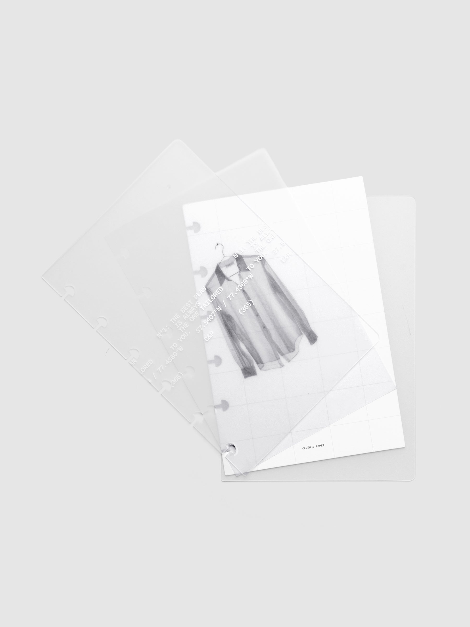 Transparent planner cover set with white printed text design and accompanying black and white dashboard with an image of a tailored shirt on a hanger shown offset. Pre-punched for discbound planners shown in size CP Petite.