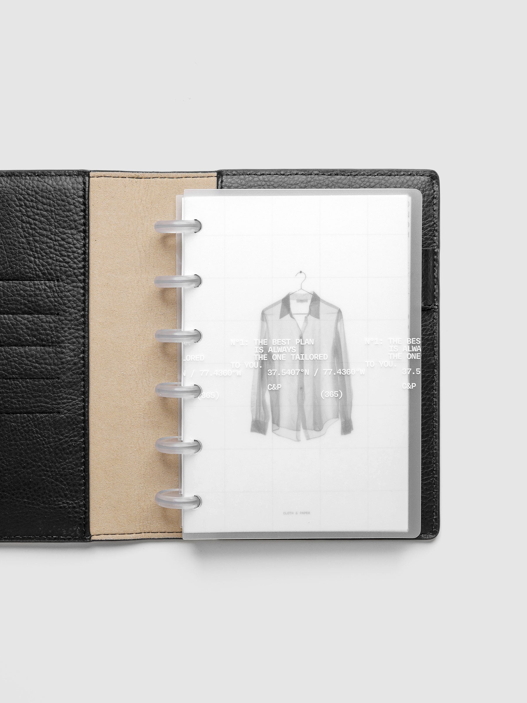 Transparent planner cover set with white printed text design and accompanying black and white dashboard with an image of a tailored shirt on a hanger. Shown discbound in a black leather folio in size CP Petite.