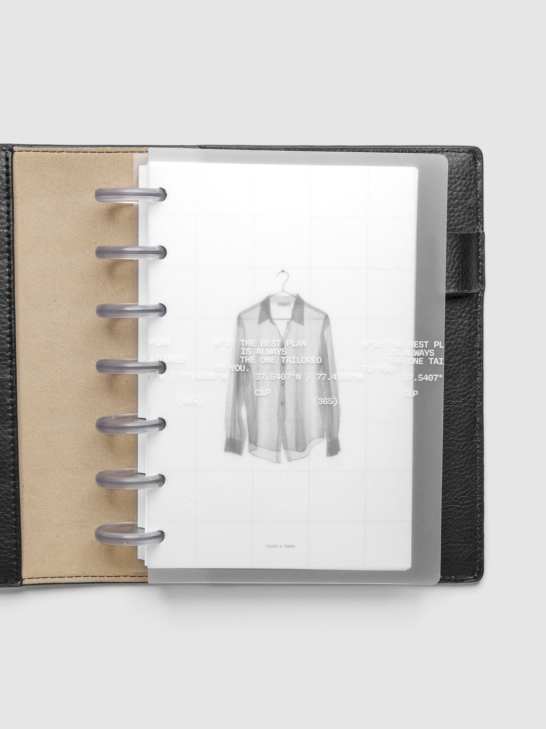 Transparent planner cover set with white printed text design and accompanying black and white dashboard with an image of a tailored shirt on a hanger. Shown discbound in a black leather folio in size HP Mini.