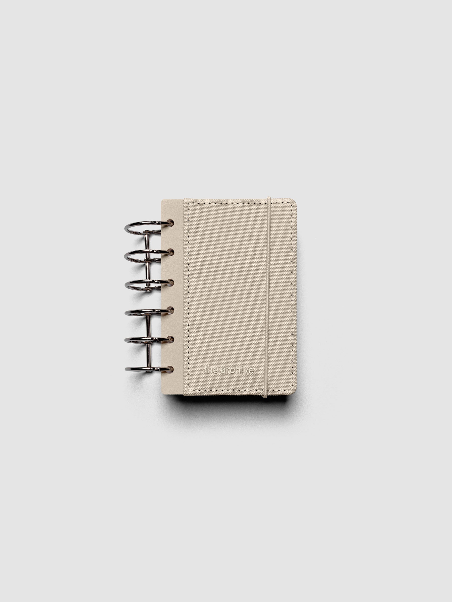 Pocket ring bound planner with a beige bookcloth cover against a grey background.