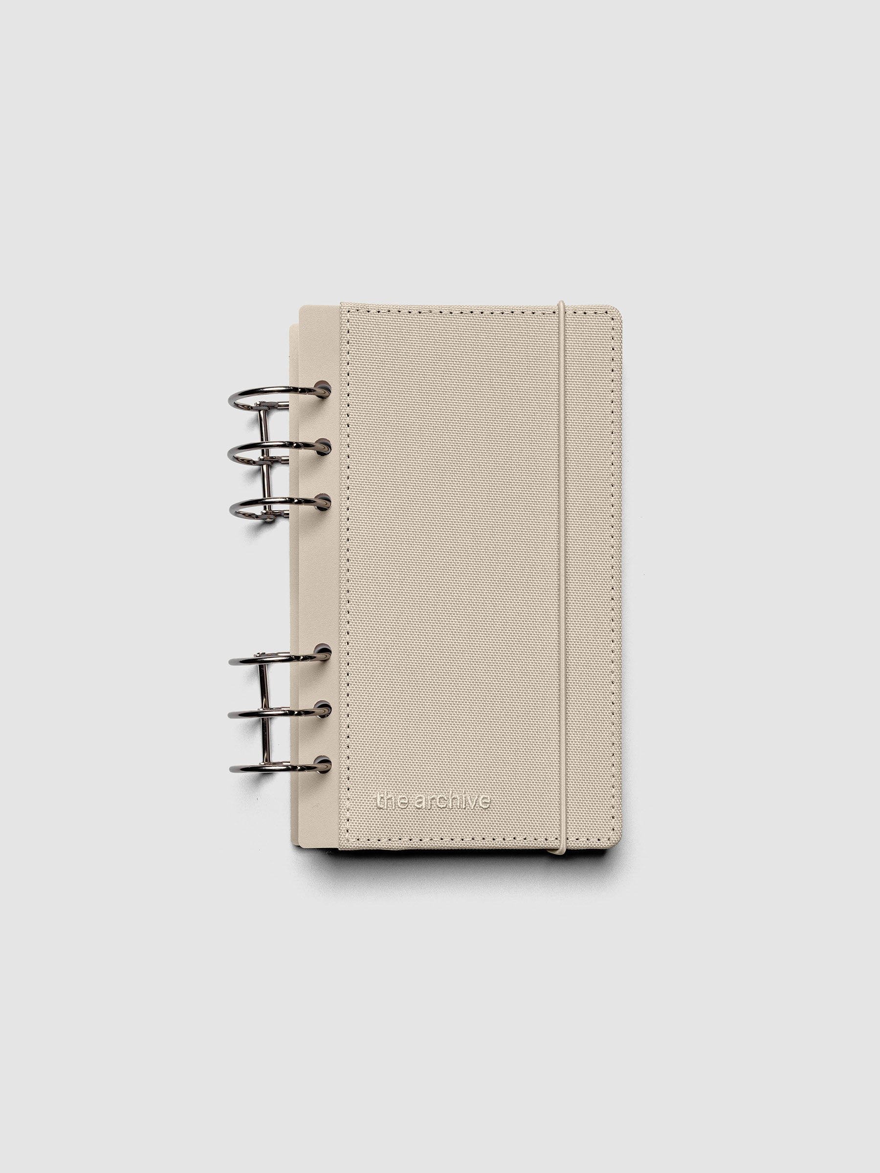 Personal ring bound planner with a beige bookcloth cover against a grey background.